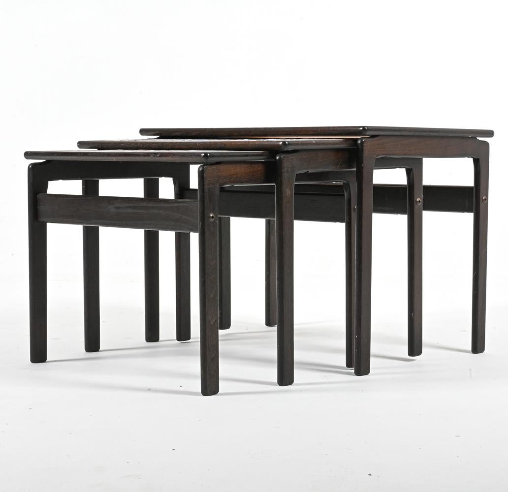 Capturez l'esprit libre des années 1970 avec cet ensemble de (3) tables d'appoint gigognes, produit par le fabricant de meubles danois Trioh Møbelfabrik en collaboration avec l'illustre studio de céramique Ox Art. 

Chaque plateau de table est