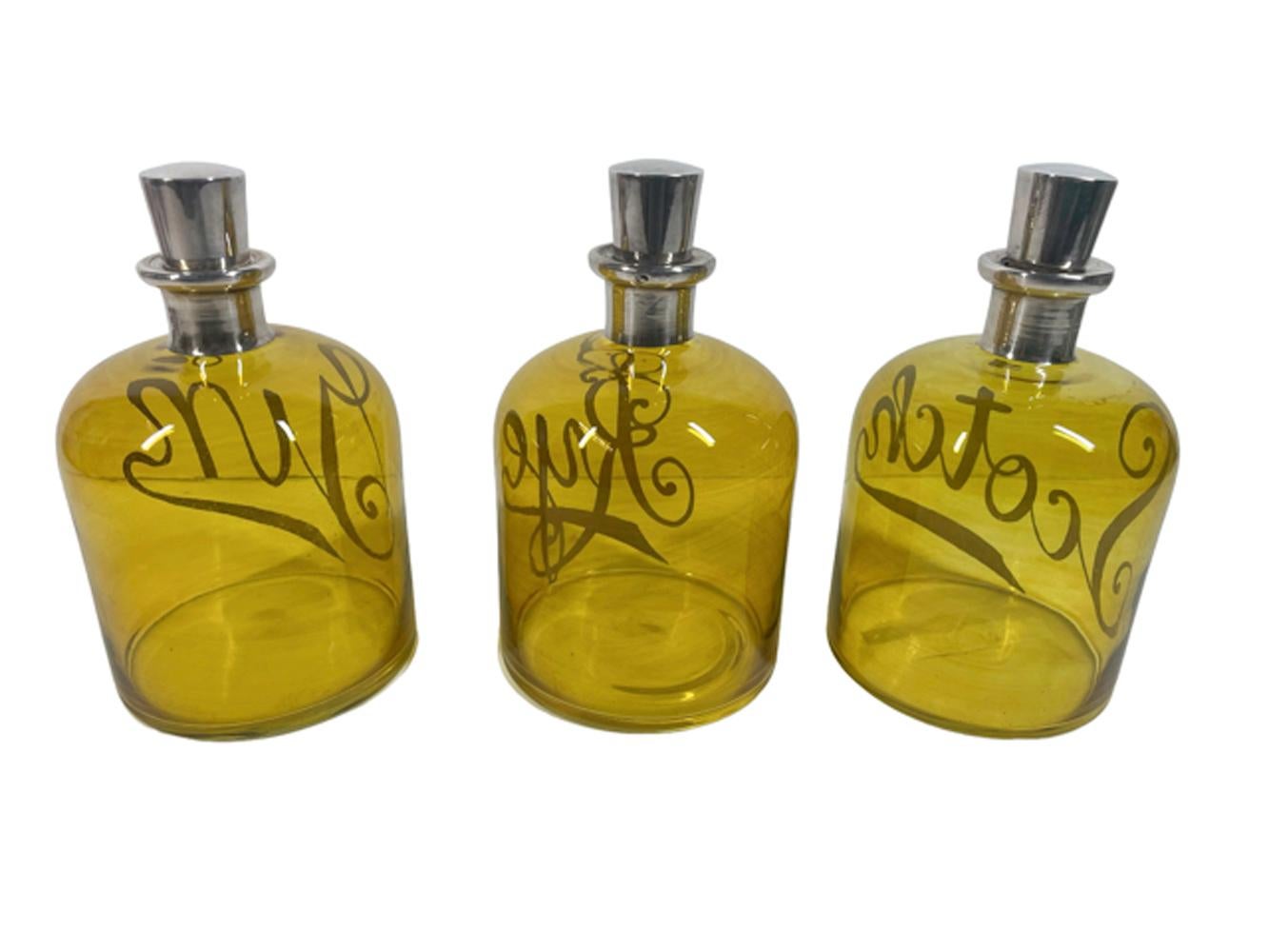Ensemble inhabituel de trois carafes ou bouteilles de bar en verre jaune/ambre avec des étiquettes argentées 
