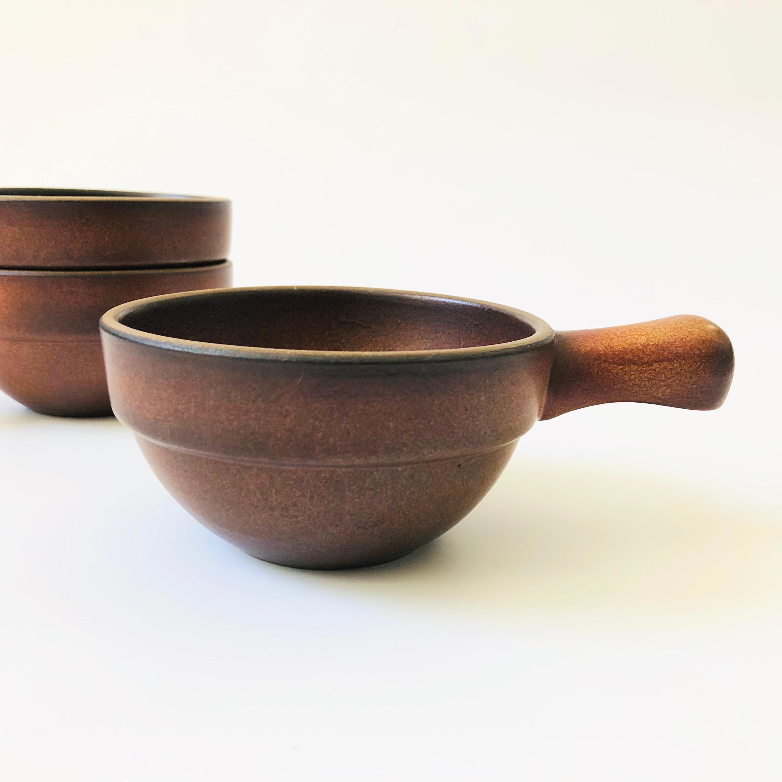 A set of 3 vintage bowls by Heath Ceramics of Sausalito. Each piece has a handle formed on one side and is finished in a lovely natural reddish brown glaze. Lovely variation to the glaze.  Marked on the base by Heath.

