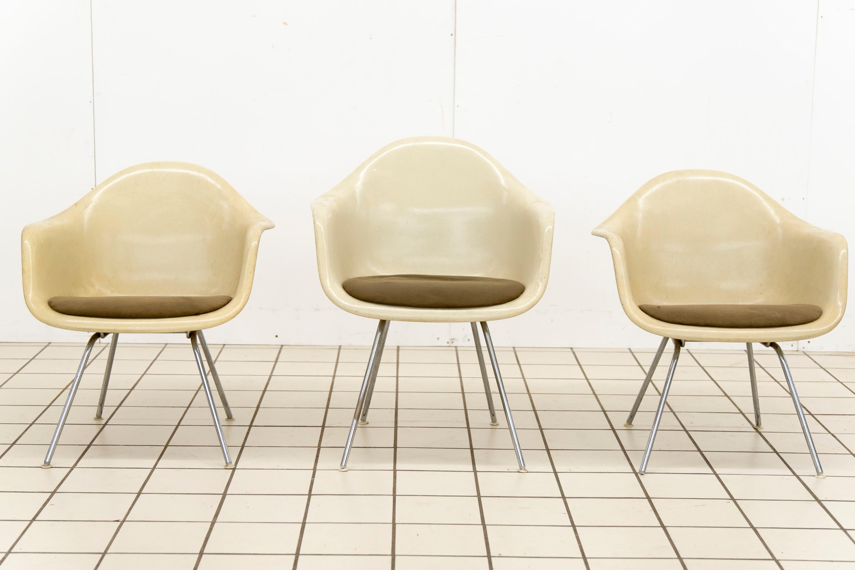This rare set of three first-generation Vitra Eames DAX (Dining Armchair with X-base) shell chairs is an iconic example of mid-century modern design. Designed by Charles and Ray Eames, these chairs showcase the pioneering use of molded fiberglass