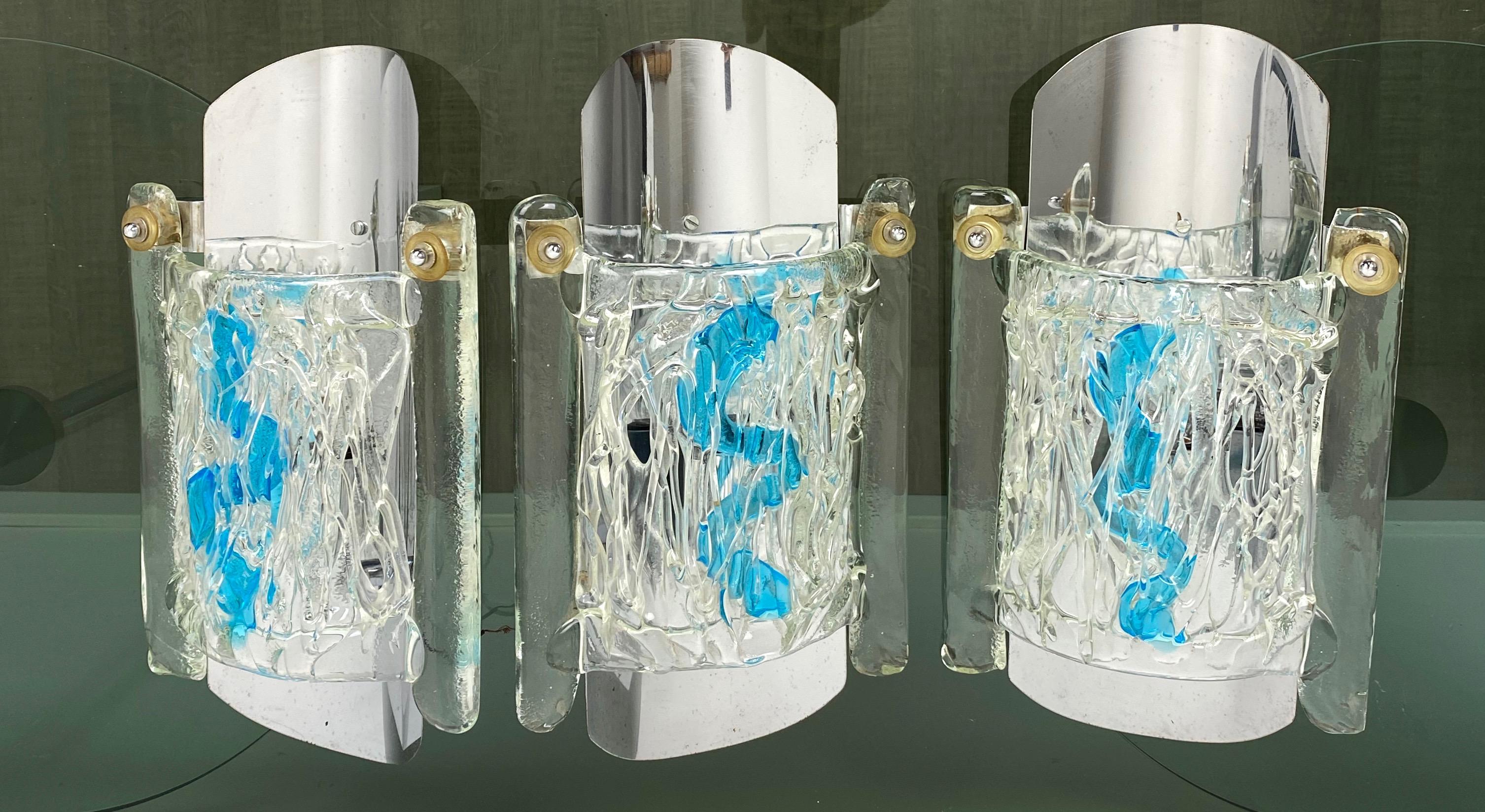 Set of three sconces by the Italian Mazzega made of chrome and Murano glass, all the three embellished with a blue line always in Murano glass. Made in Italy in the 1970s.