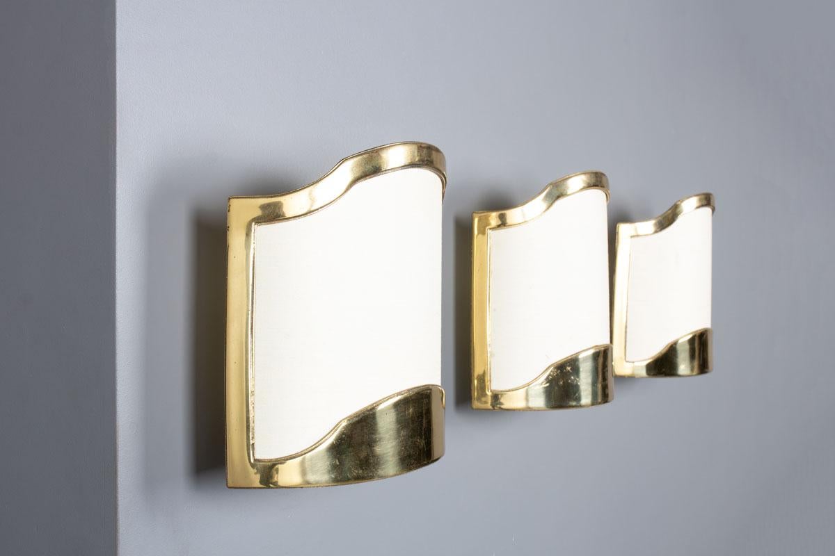 Conjunto de 3 apliques de los años 50 en Francia
Soporte de pared y reflector de media luna curvada
Latón y tejido de seda beige
Modelo chic