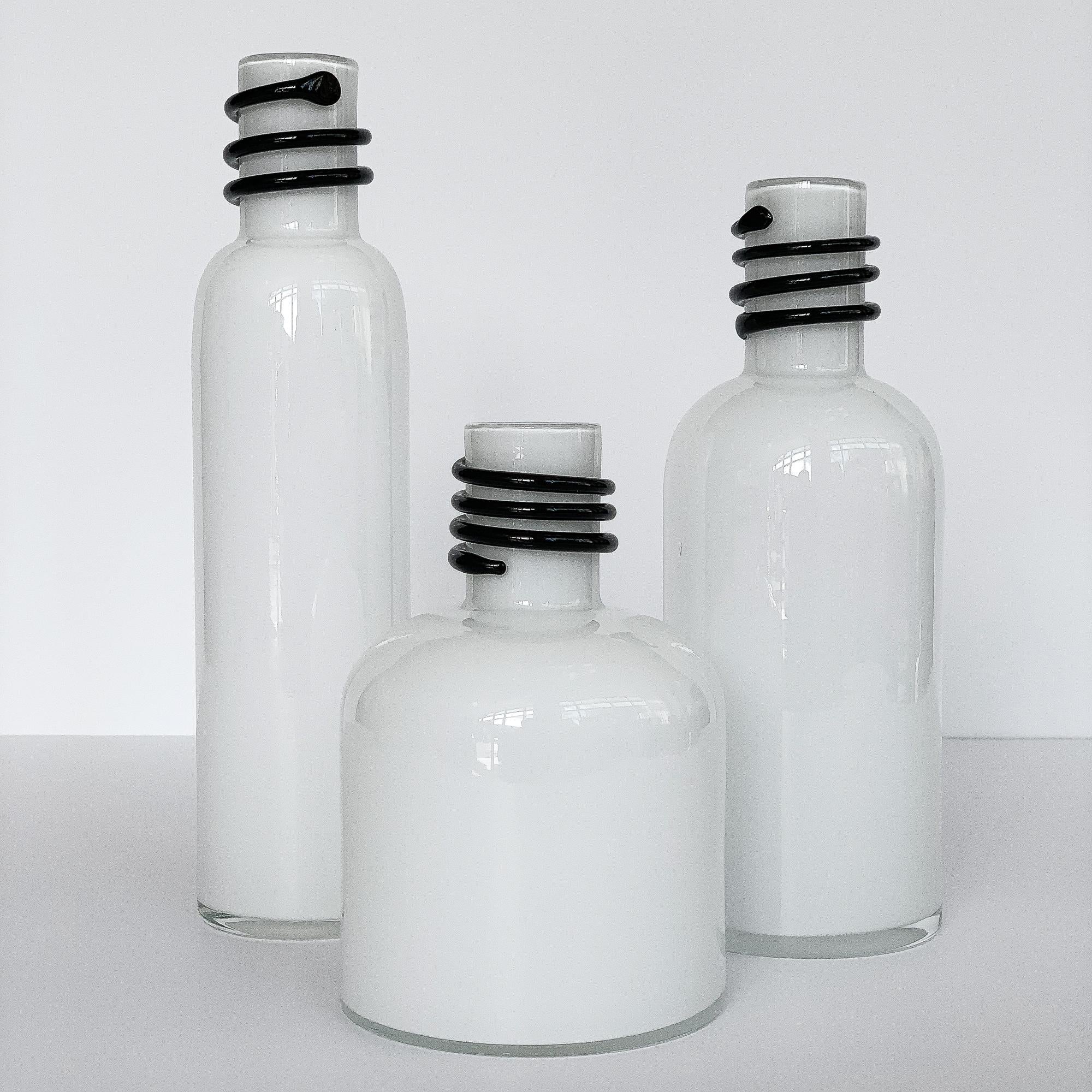 Set of 3 handmade cased glass vases / bottles by Jerzy Sluczan-Orkusz for Tarnowiec, circa 1980s, Poland. From the Butli series. White cased glass with an applied spiral of black glass around each neck. Perfect for any Postmodern / Memphis interior!