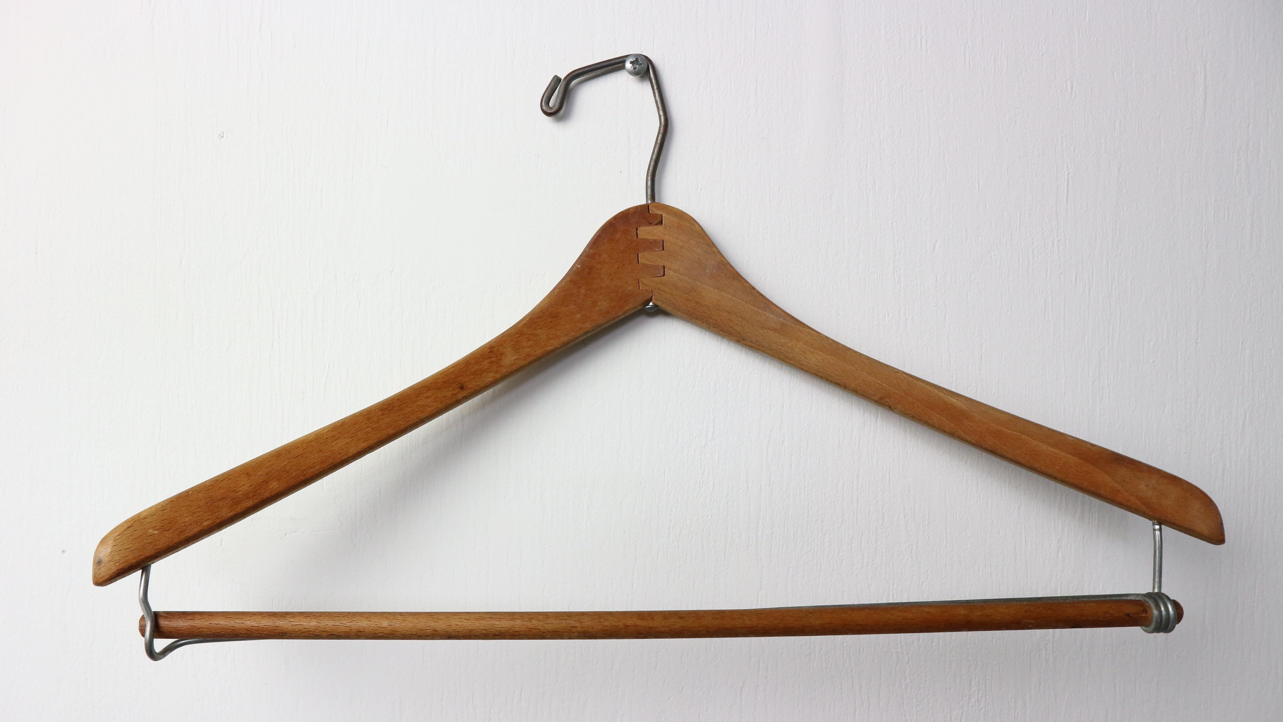 It is an old hanger, made of wood reinforced with wire and still very robust. Beautiful curved suit hanger with metal hook and locking pants bar.
But can also be used very decorative to hang posters, cards or pictures.

The hanger is handmade