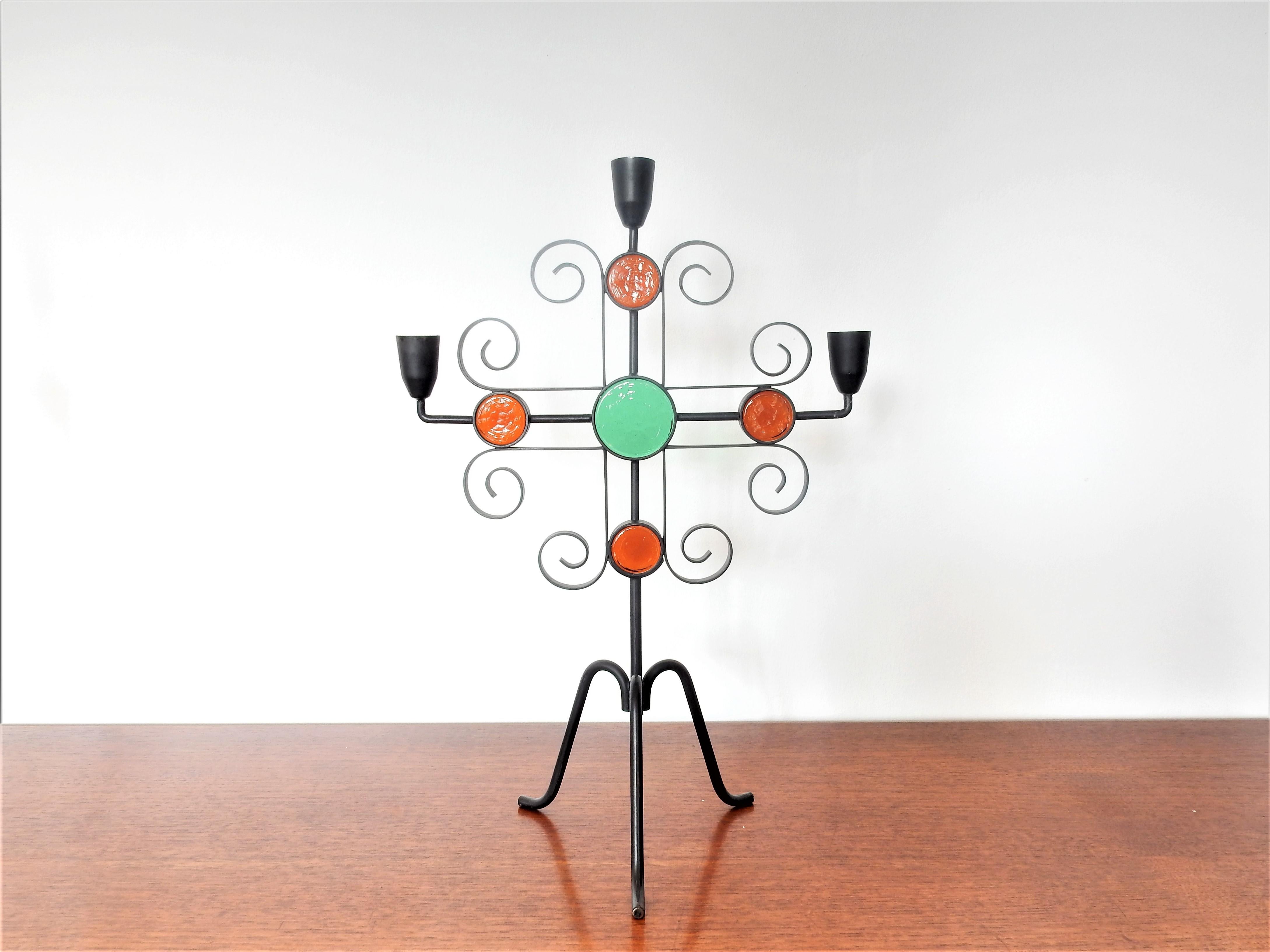 This elegant set of candelabra or candleholders was designed by Gunnar Ander for Ystad Metall in Sweden in the 1960s. The tripod candelabra is made of a black painted wrought iron frame with lighter and darker orange and green round glass inserts. A