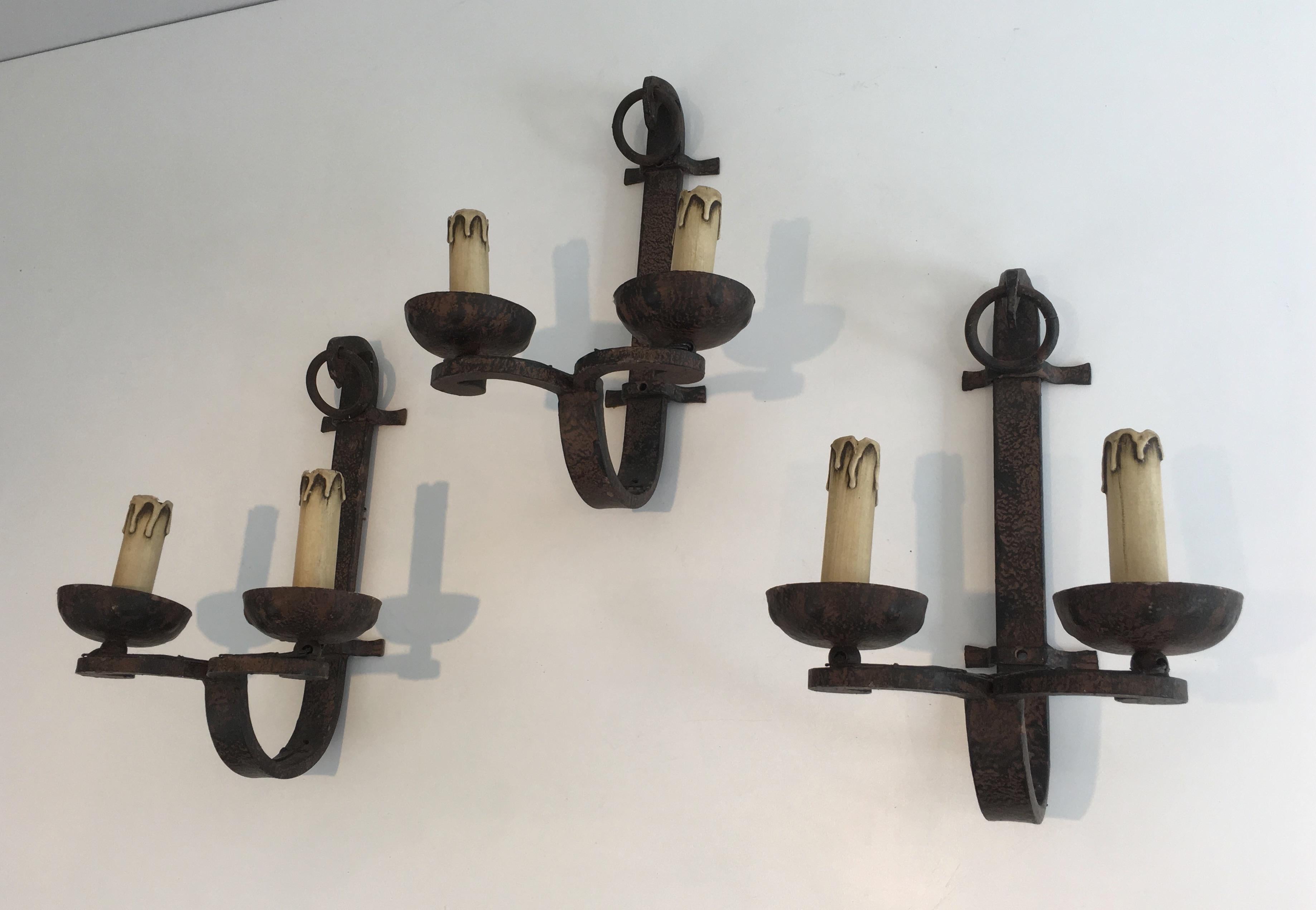 This set of 3 wrought iron wall sconces is French, circa 1950. These wall lights can also be sold individually.