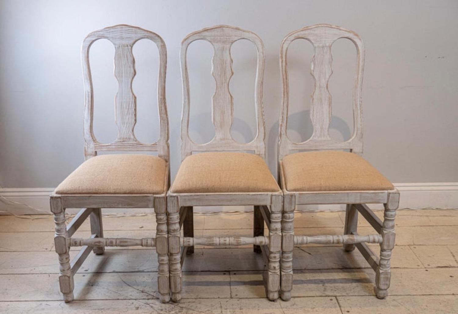 Set of 4 Swedish Folk chairs which feature high-backs and drop-in seats. Upholstered in a neutral sacking fabric. The paintwork has been scraped back and refreshed with a simple white wash.

A wonderful set of chairs which are perfect for a