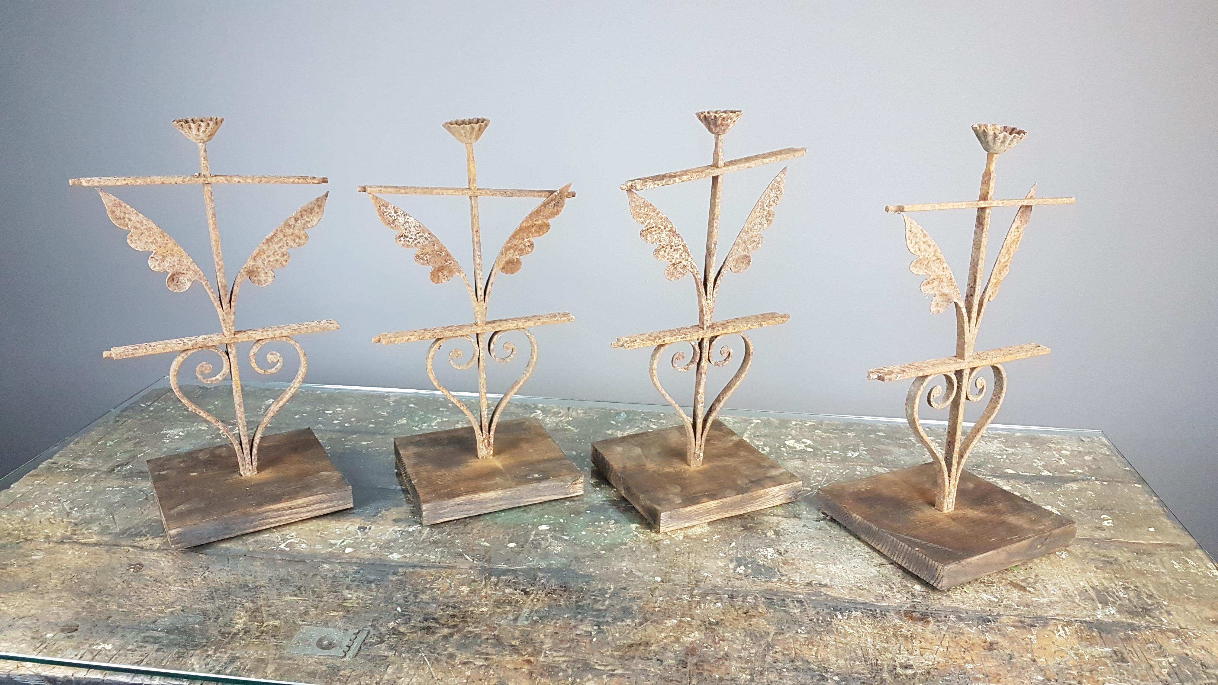 A group of 4 very decorative weathered 19th century wrought iron railing tops on stands. They are flower and leaf formations in the iron and the bases are scored pitch pine to give a good weight. They measure 18.5cm square at the base and 45cm high.