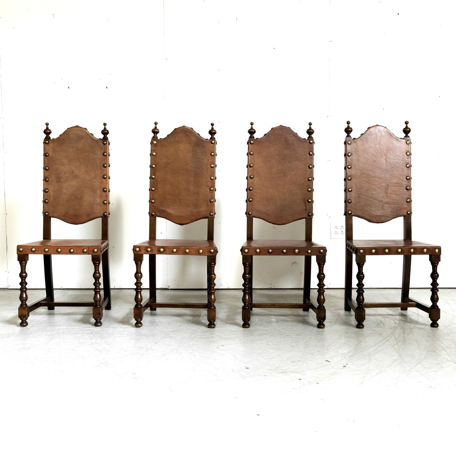 A handsome set of four 19th century Spanish Baroque style leather and walnut side dining chairs, circa 1890s. Original cordovan leather backs and seats with wood finials and large brass nailhead trim. Supported by two front turned legs and straight