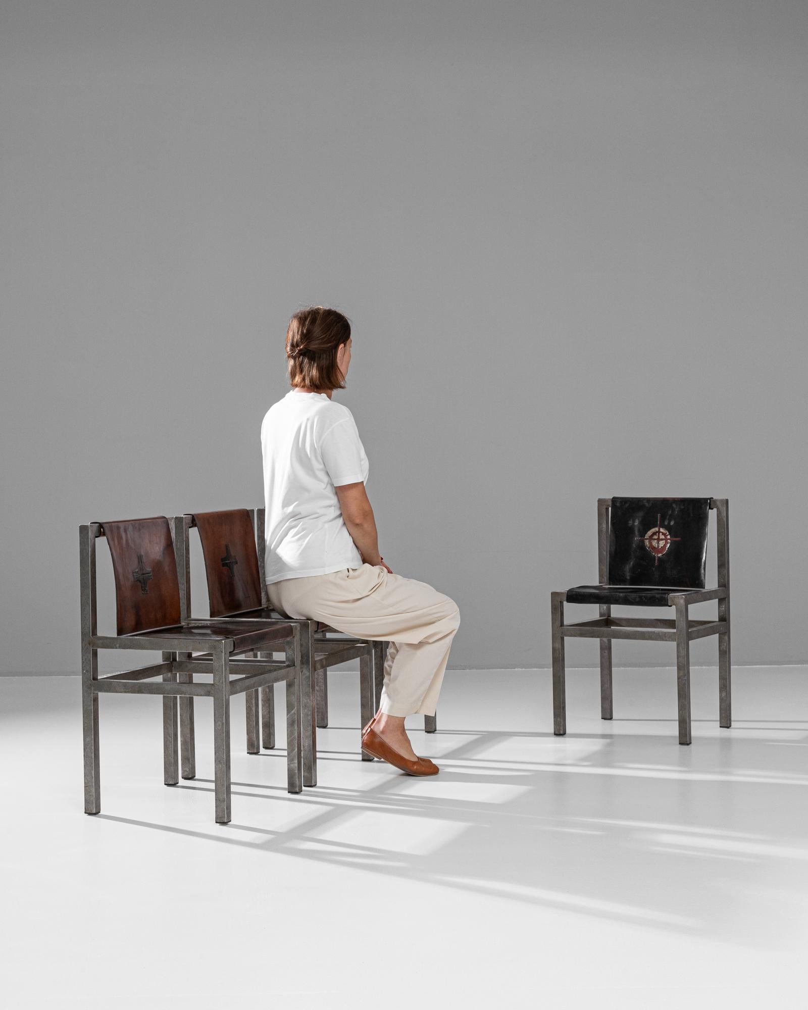 Questo esclusivo set di quattro sedie da pranzo, realizzato in Francia a metà del XX secolo, combina strutture metalliche in stile industriale con sedute in pelle rustica per un look distintivo. Le sedie sono caratterizzate da una solida struttura