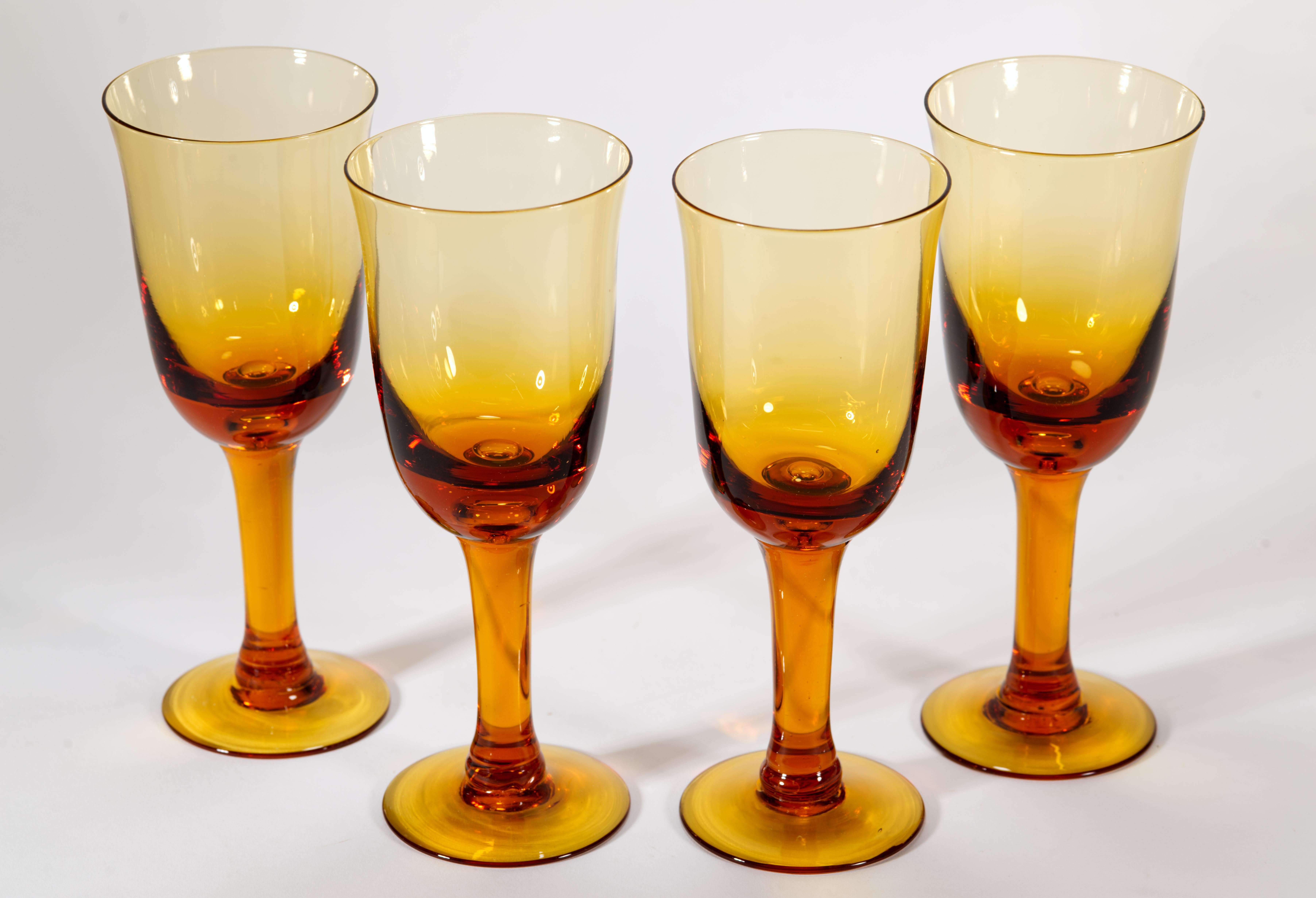  Set of 4 goblets can be used either as wine or water glasses. The goblets are hand blown of deep, almost honey-hued amber glass, with a large controlled bubble at the base of the bowl adding visual interest to minimally shaped pieces. Lightly