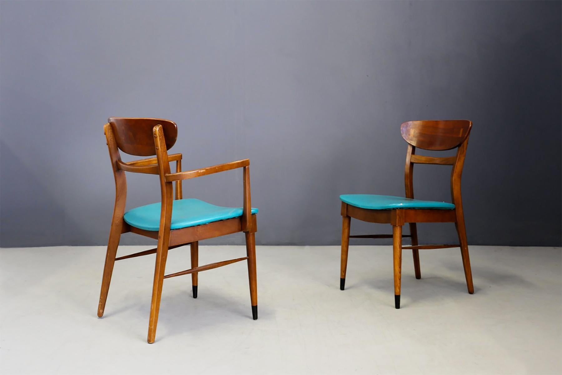 Beautiful American set composed of four chairs in wood and leather.
American chairs set includes two table head chairs with arms and two chairs for diners without arms. 
The seats of the American chairs were made of leather in yellow and turquoise