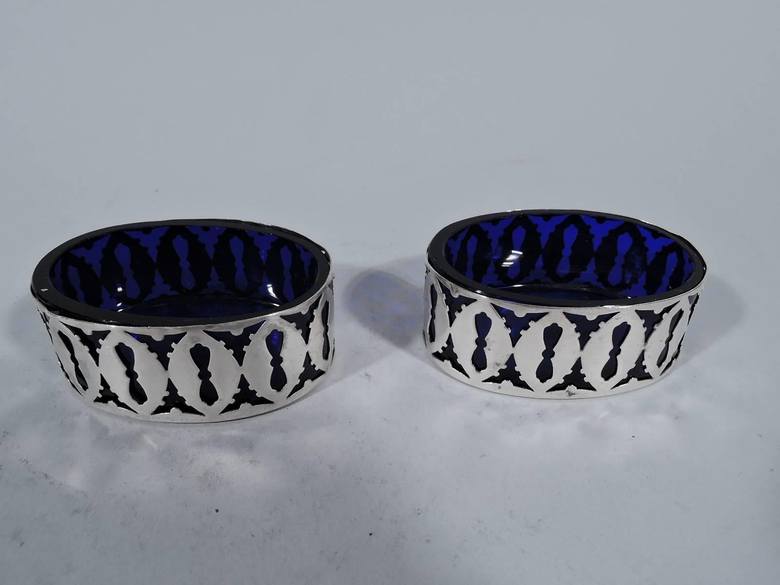 Set of four Edwardian sterling silver open salts. Made by Watrous (a division of International) in Wallingford, Conn., circa 1910. Oval bowl has straight sides with pierced keyhole motif. With cobalt glass liner. Hallmark includes no. 50. Total