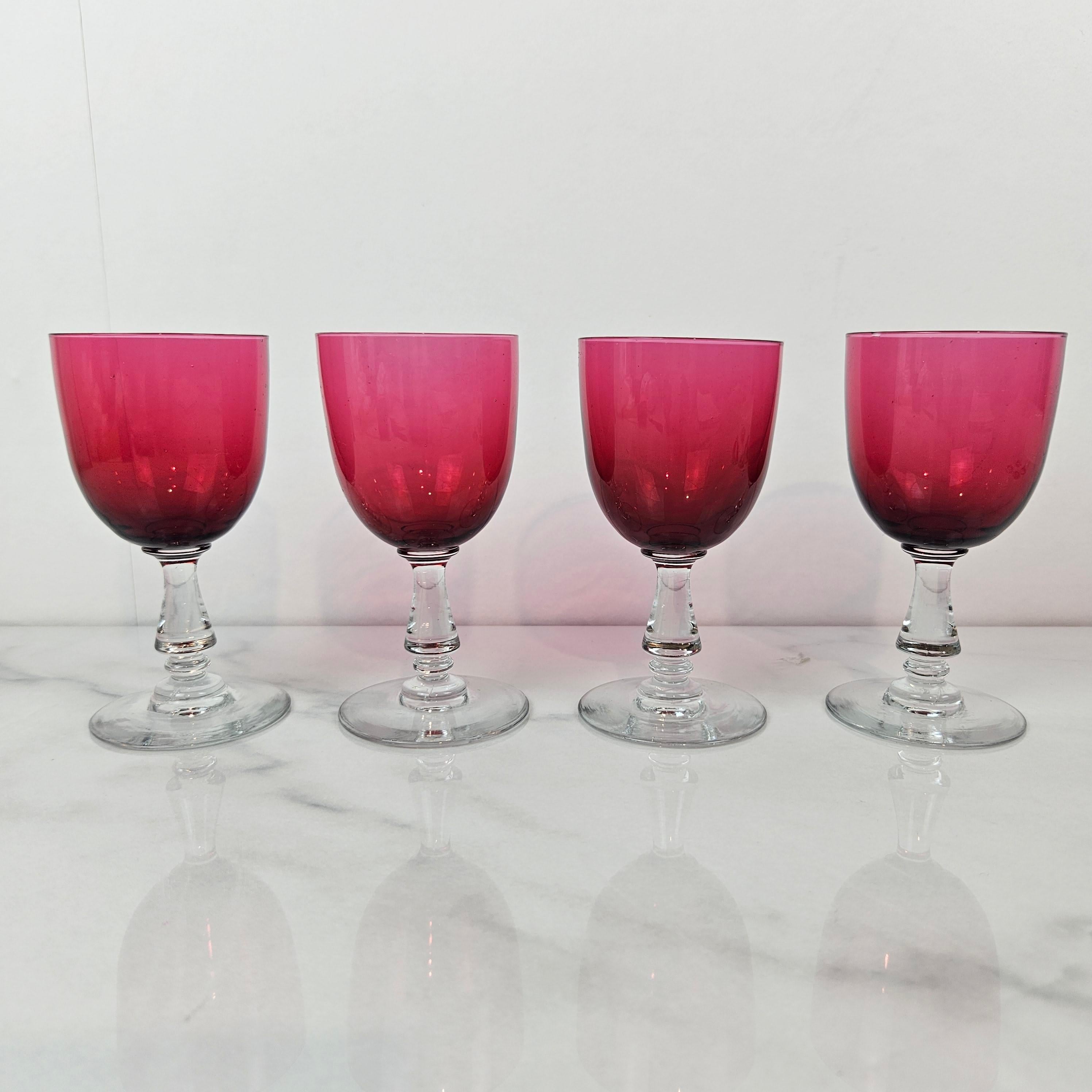 Elegant set of four antique cranberry glass goblets made in the United Kingdom around 1890. 
Each goblet features a beautifully hand-blown bowl in a deep cranberry hue, set upon a clear, turned stem with a subtle knop detail above a wide circular