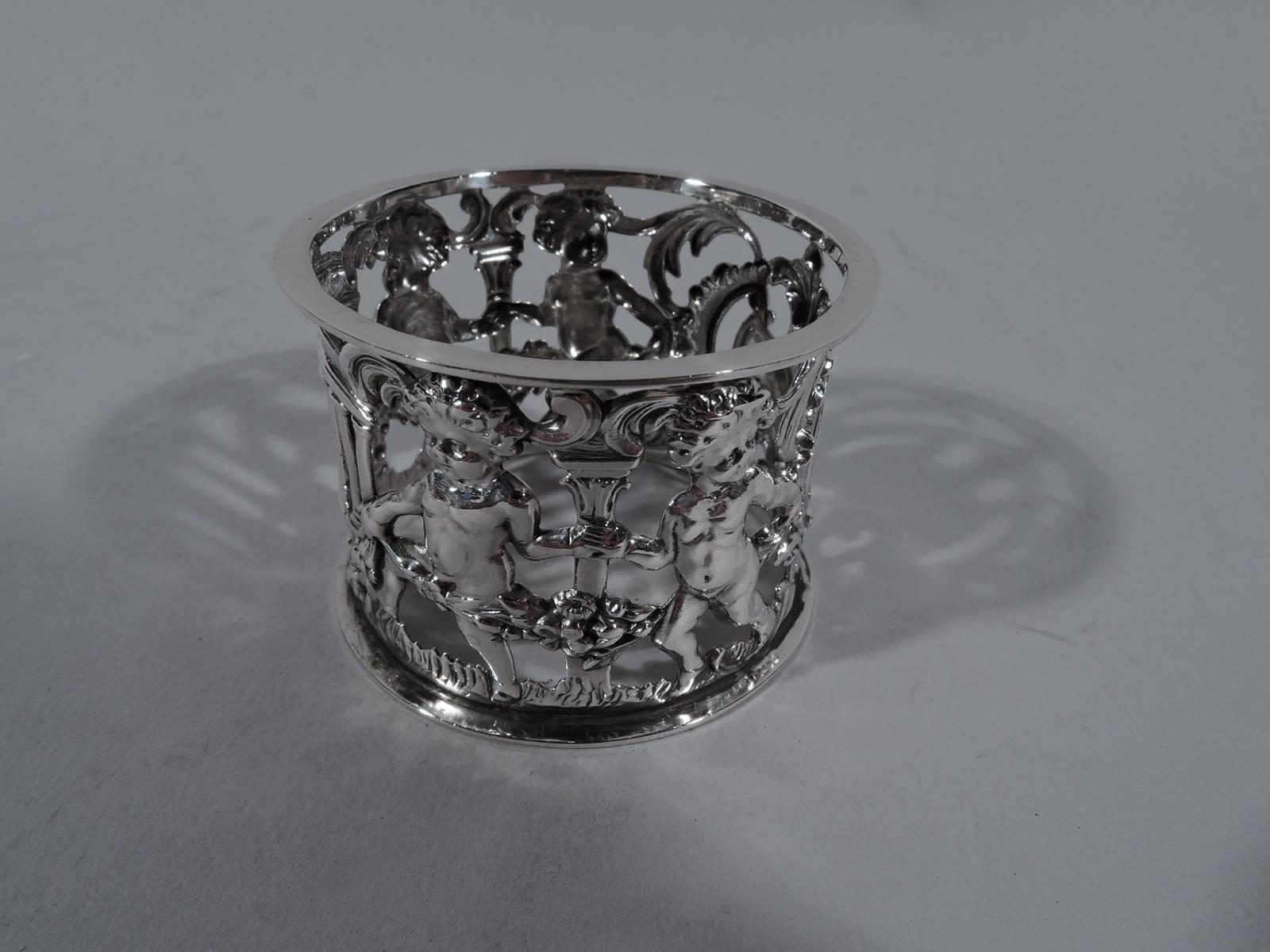 English Edwardian sterling silver napkin rings, 1906-1907. Each: Open sides with classical colonnade and cherubs dancing with garland, which they carry, climb over, and thread between their chubby thighs. Frothy classicism. Armorial cartouche