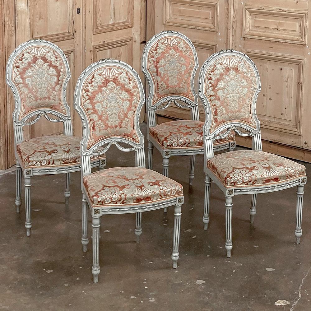 Set of 4 antique French Louis XVI painted chairs will make a classic addition to any decor! The ovoid shield shaped seat back and generous seat are framed in incredibly detailed carved fruitwood, styled with spiral ribbon, fabric swags and acanthus