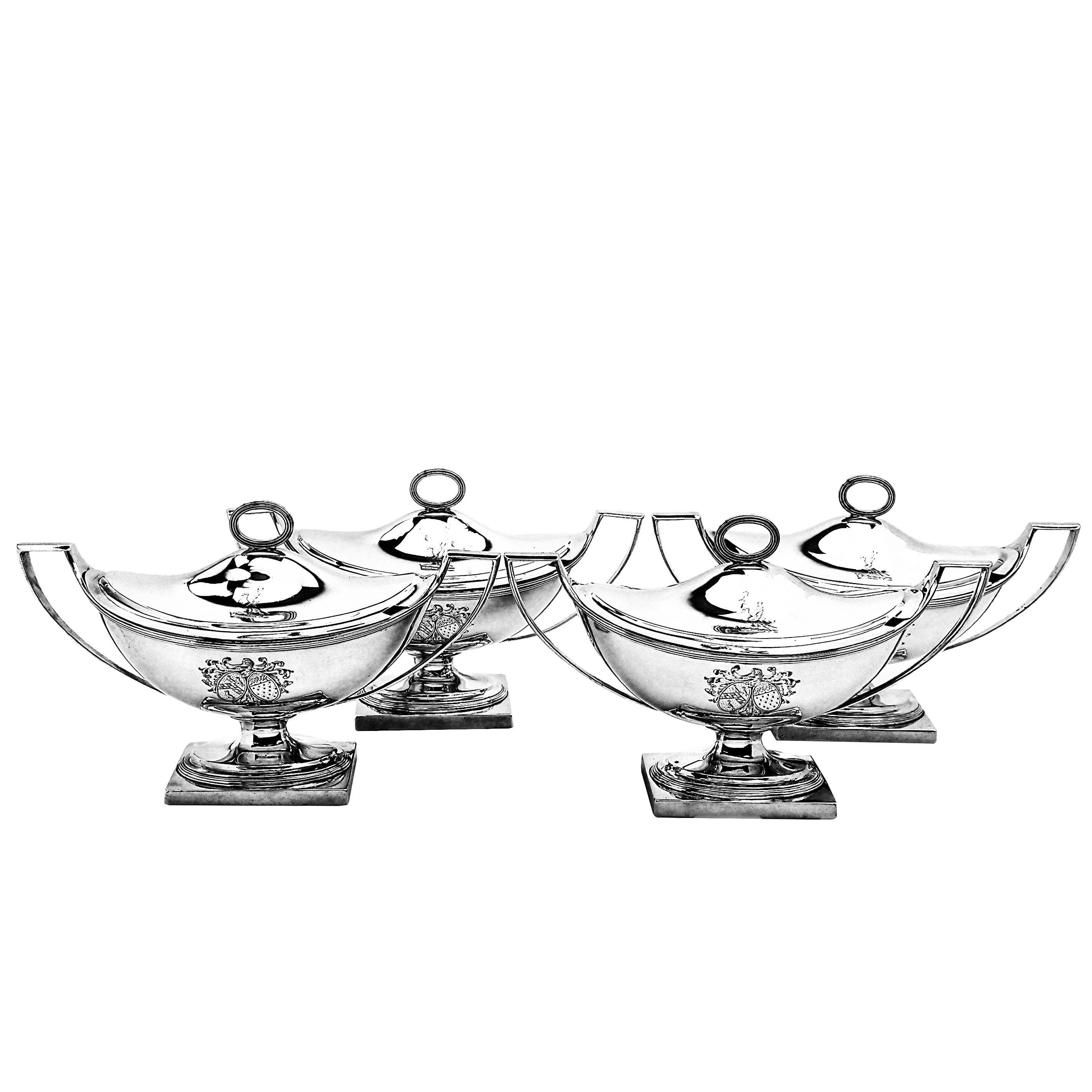 A set of four Antique George III solid Silver Sauce Tureens in a Classic oval form and standing on a square base. Each Tureen has a pair of impressive handles and the fitted domed lids have a reeded oval finial. Each Tureen has a large engraved