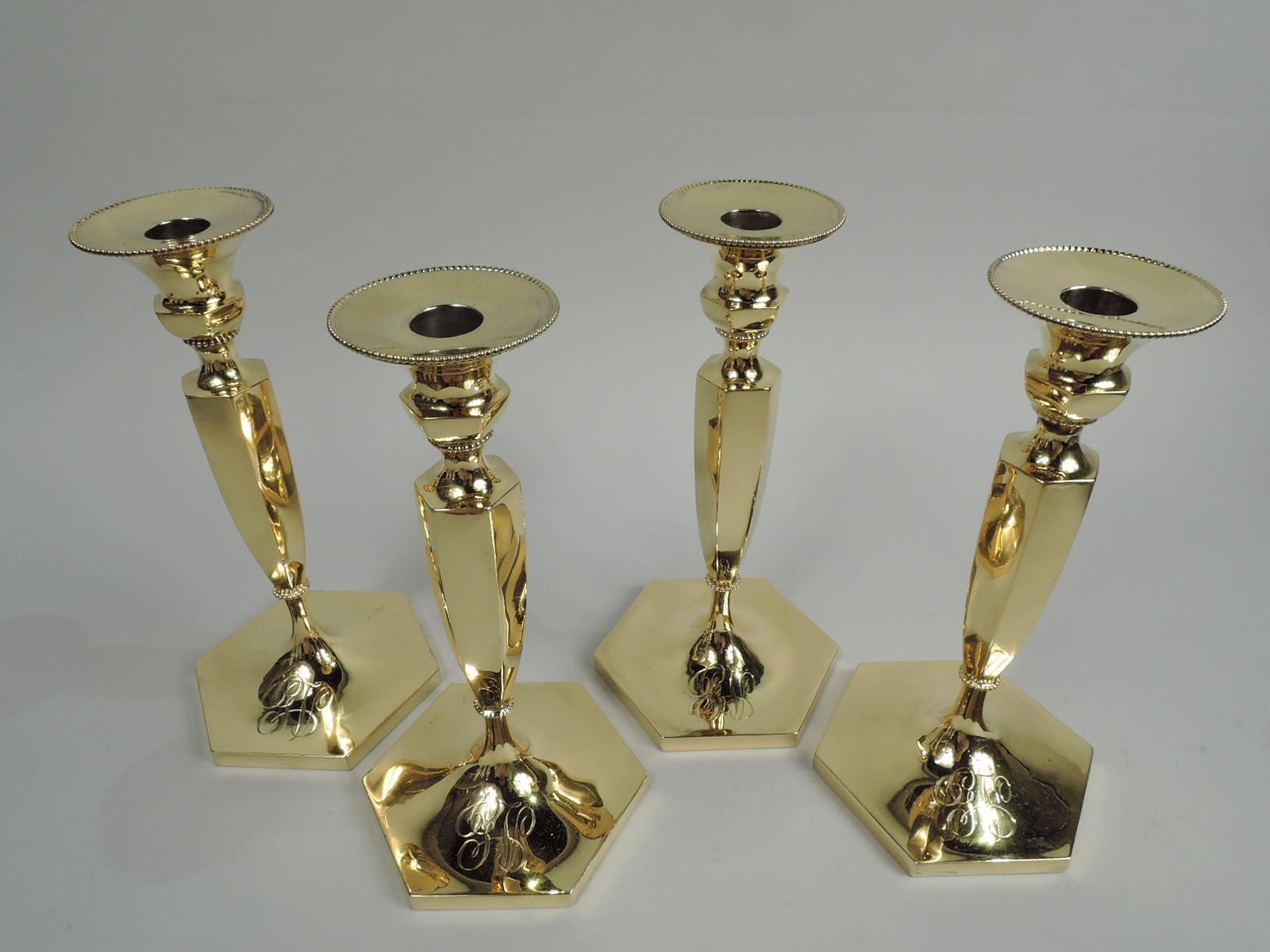 Set of 4 Sumptuous Victorian Classical gilt sterling silver candlesticks. Made by Howard & Co. in New York, ca 1894. Each: Bellied socket with detachable bobeche on spool support on tapering shaft on raised foot. Faceted. Interlaced script monogram