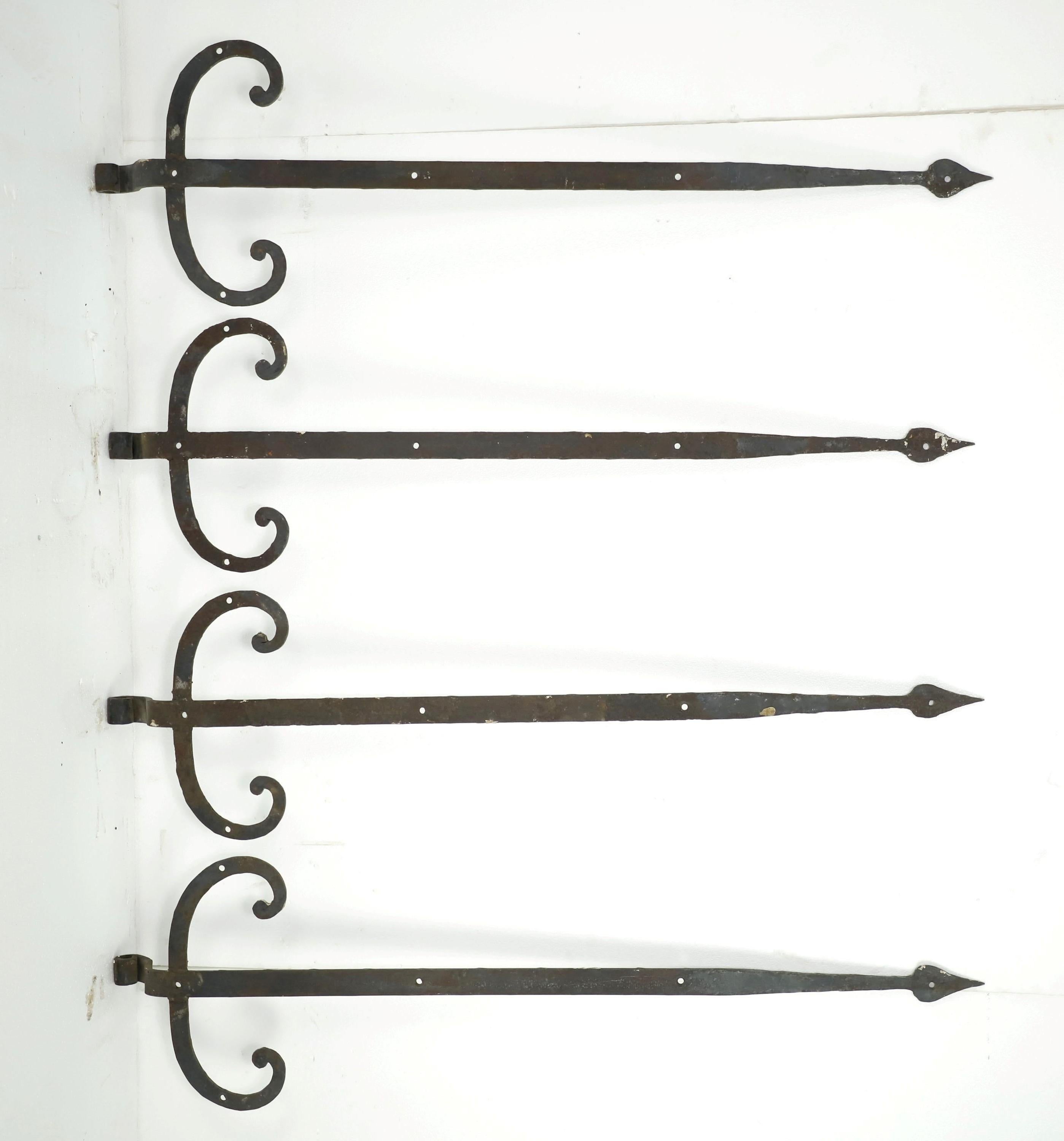 Black antique spear shaped hand forged wrought iron strap hinges with curled details on the sides. They are in good condition. Priced as a set. Please note, this item is located in our Scranton, PA location.