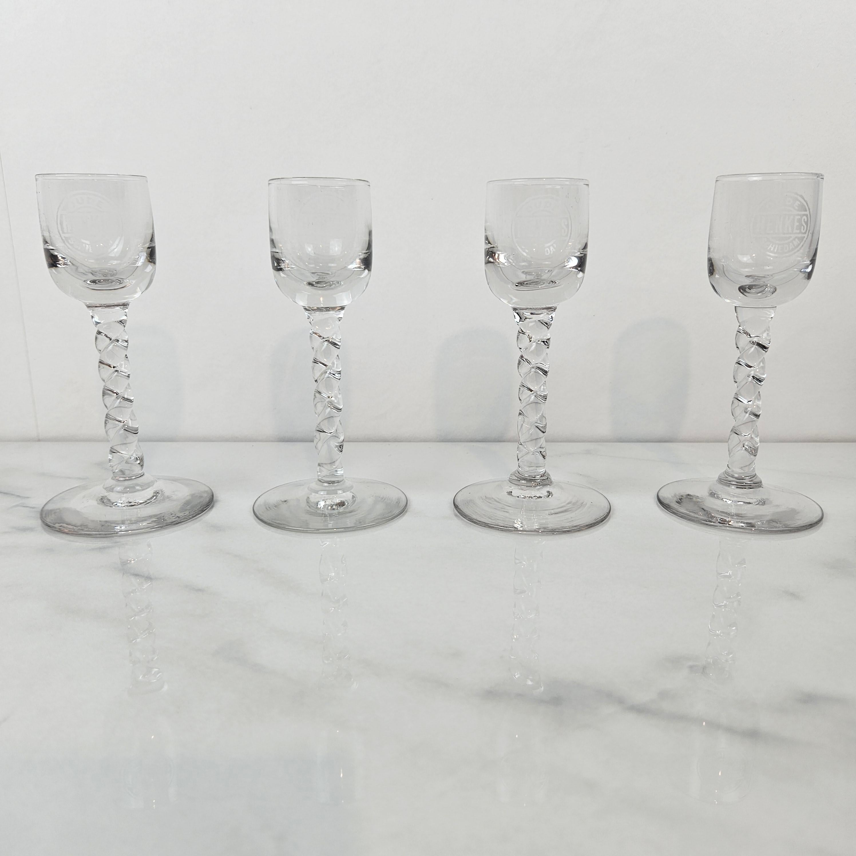 A rare and beautiful set of four antique handblown jenever glasses, engraved with the inscription “Oude Henkes Schiedam.” 
Dating from around 1900, these elegant glasses feature clear bowls delicately etched with text and slender stems with a