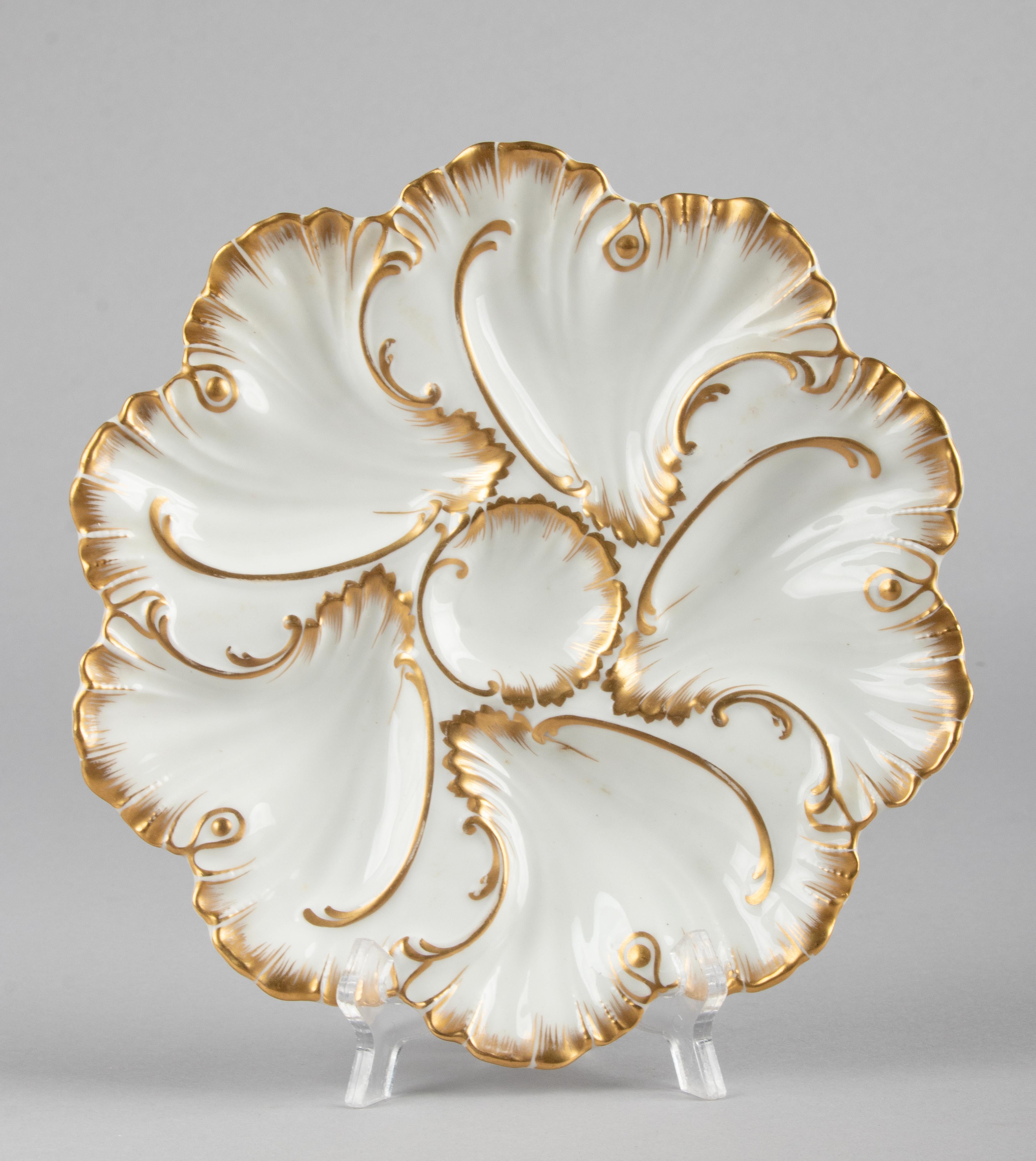 Set of four antique porcelain oyster plates. The plates are beautifully decorated with gold-coloured accents. The plates date from circa 1900, they are marked on the back with the monogram A.L, which stands for Alfred Lanternier Limoges. The plates
