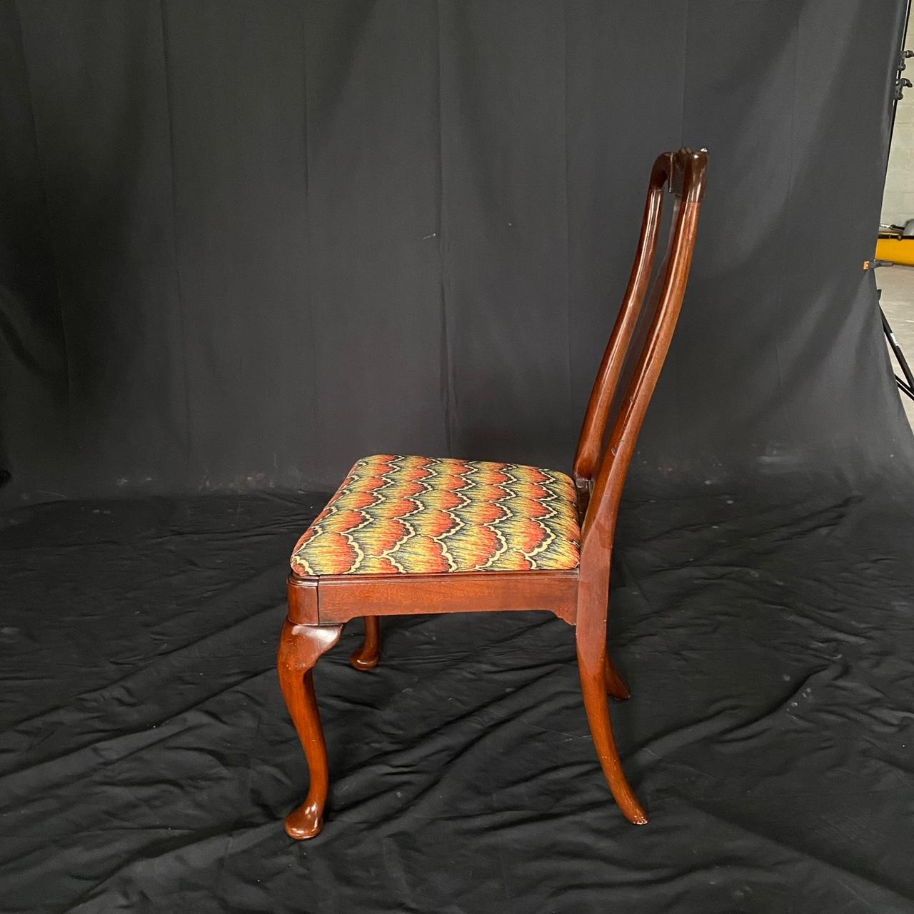 Set of 4 antique Queen Anne mahogany dining chairs having ergonomically curved seatbacks with solid splats connecting to a generously sized seat with lovely immaculate mid century upholstery. A framework surrounds the seat creating a simple apron,