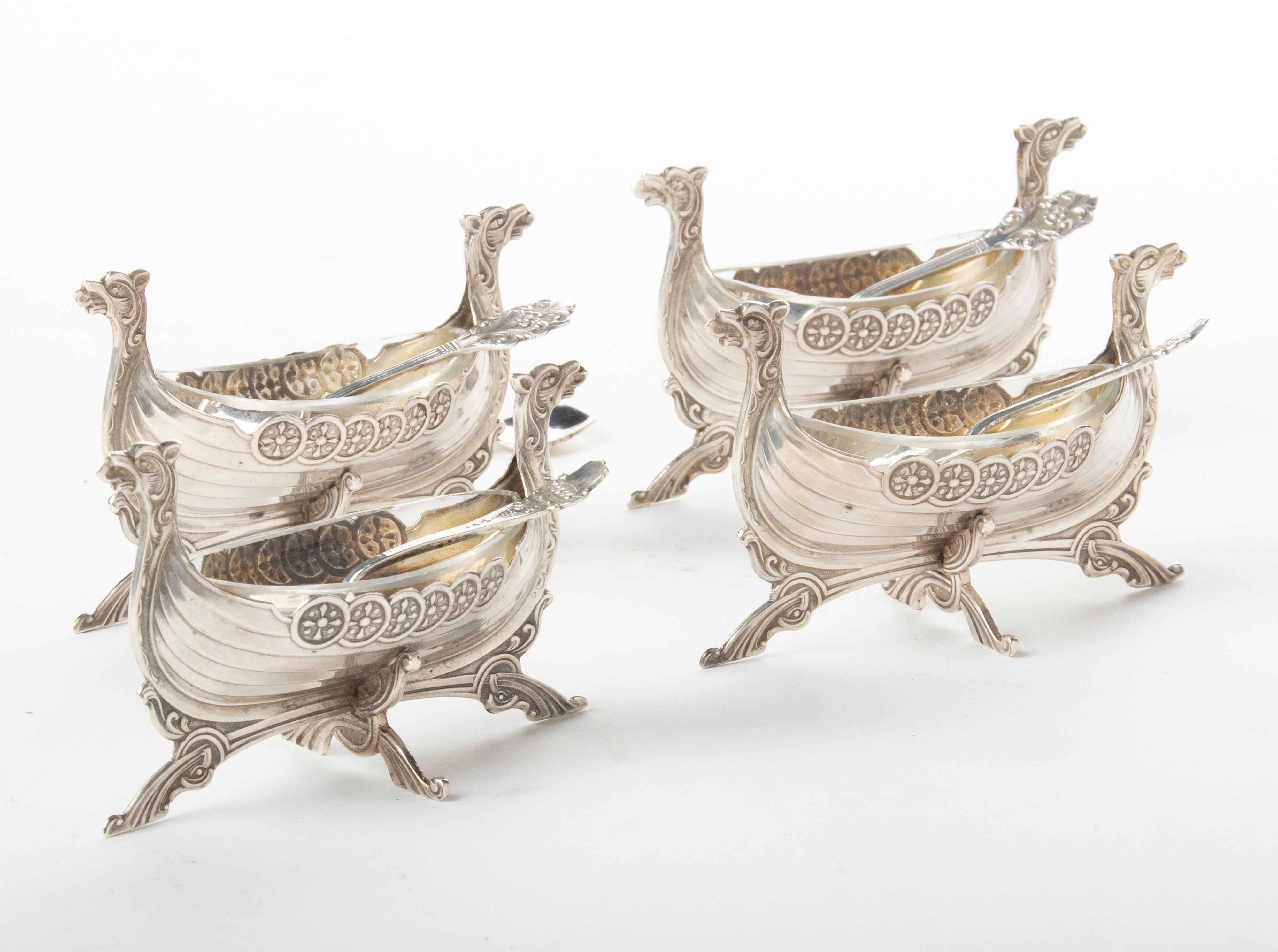 Set of four silver salt bowls, shaped like Viking boats. The bowls have a removable glass inner bowl that fits exactly in the boat. These bowls come with three very small salt spoons with the Viking boat theme, and two other small salt spoons. The