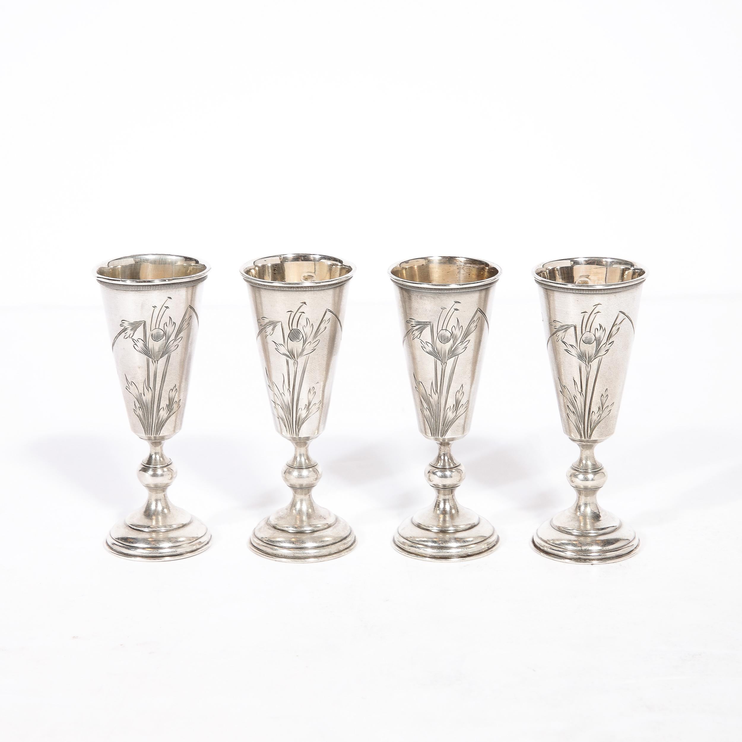 This beautiful set of four antique sterling silver Kiddish cups were realized in Russia, circa 1885. They feature circular tiered bases with undulating stems complete with a spherical detail. The elongated subtly conical cups are hand inscribed with