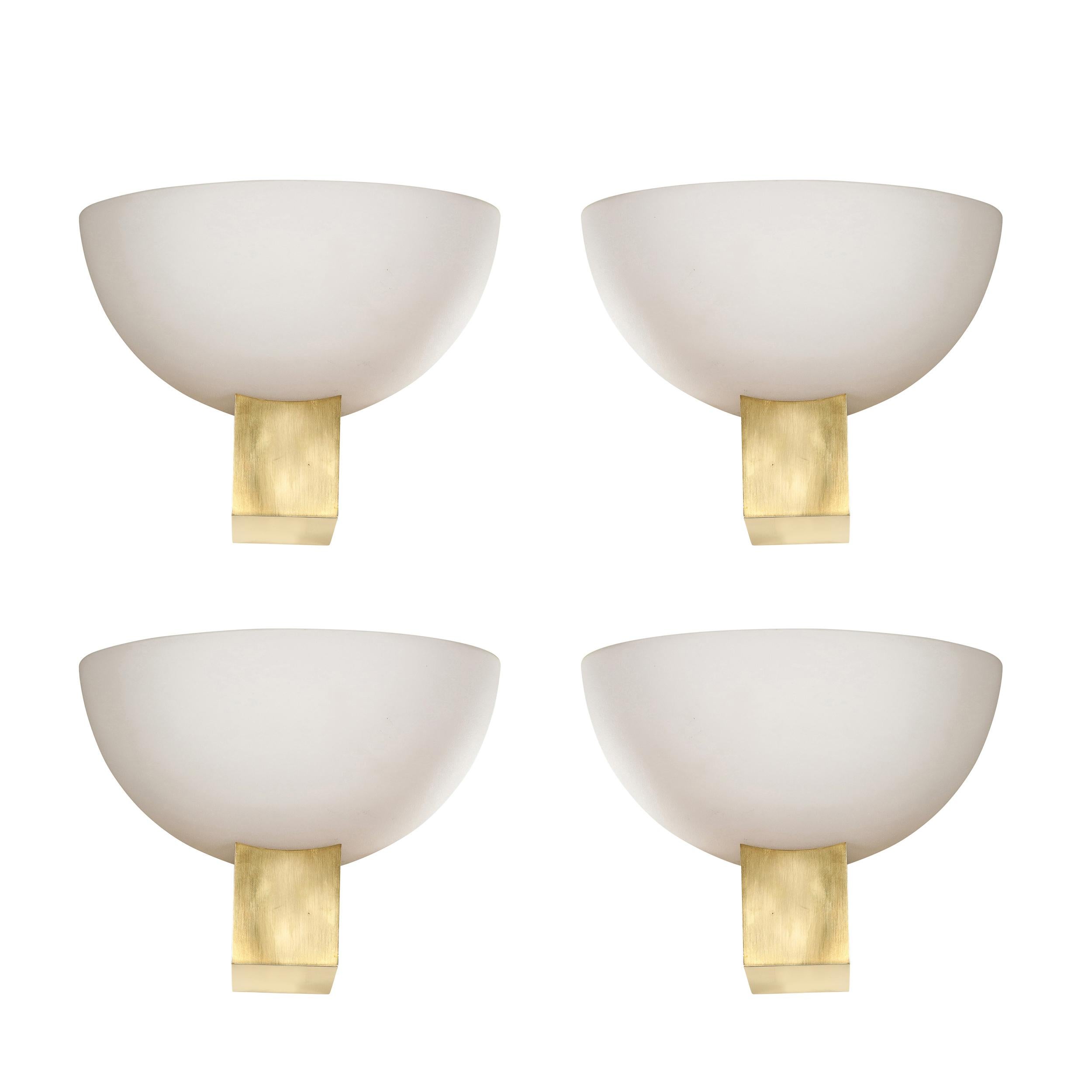 This sophisticated and stunning set of four Art Deco brass and frosted glass reverse dome sconces were realized by the esteemed atelier of Jean Perzel in France circa 1940. They feature volumetric rectangular bodies in brass that cantilever out from