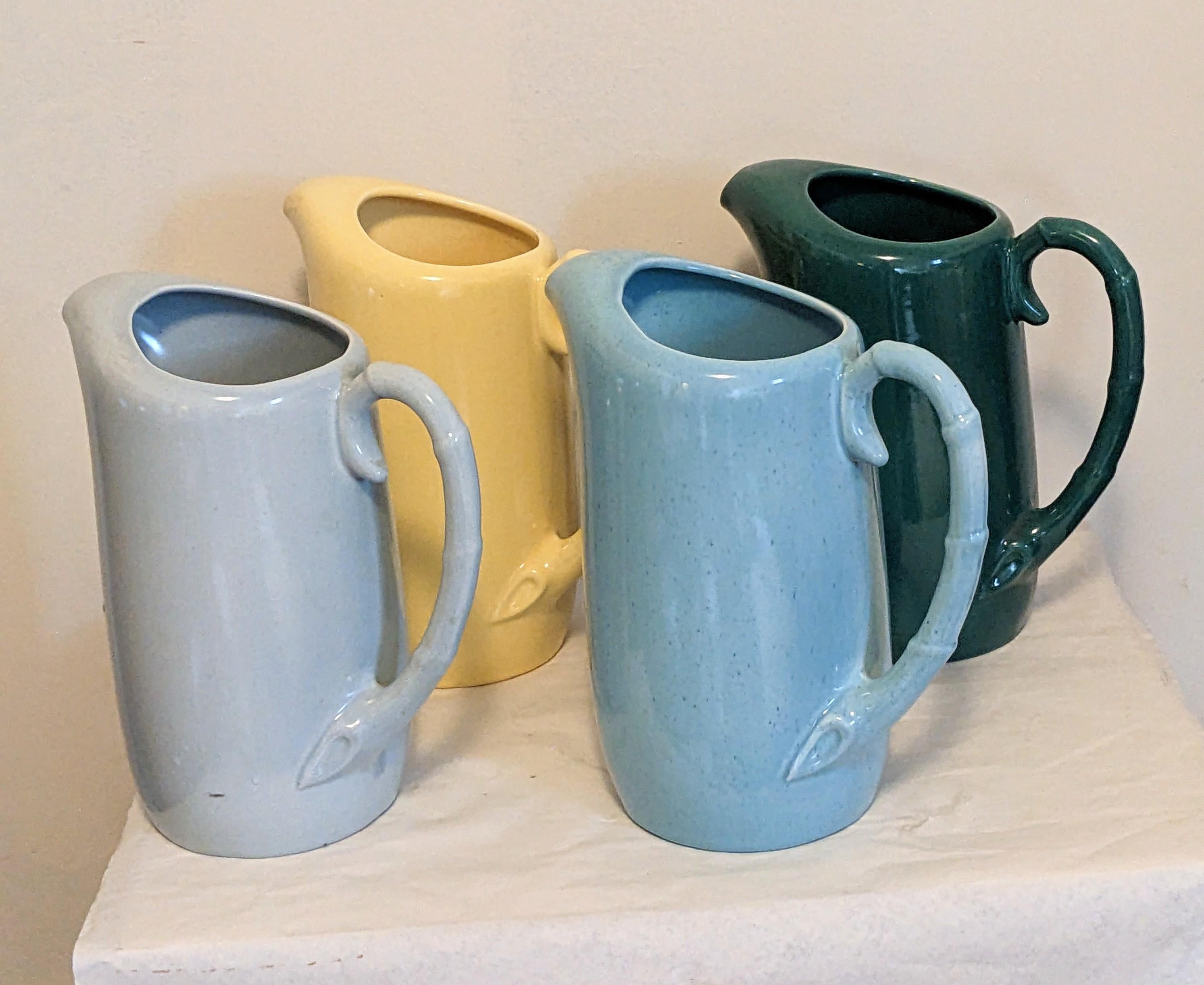 Set of 4 Art Deco Pottery pitchers attributed to Bauer Pottery, perfect for an instant splash of color in your decor. Great display pieces, each with a curved bamboo handle. 
Measures: Body 10