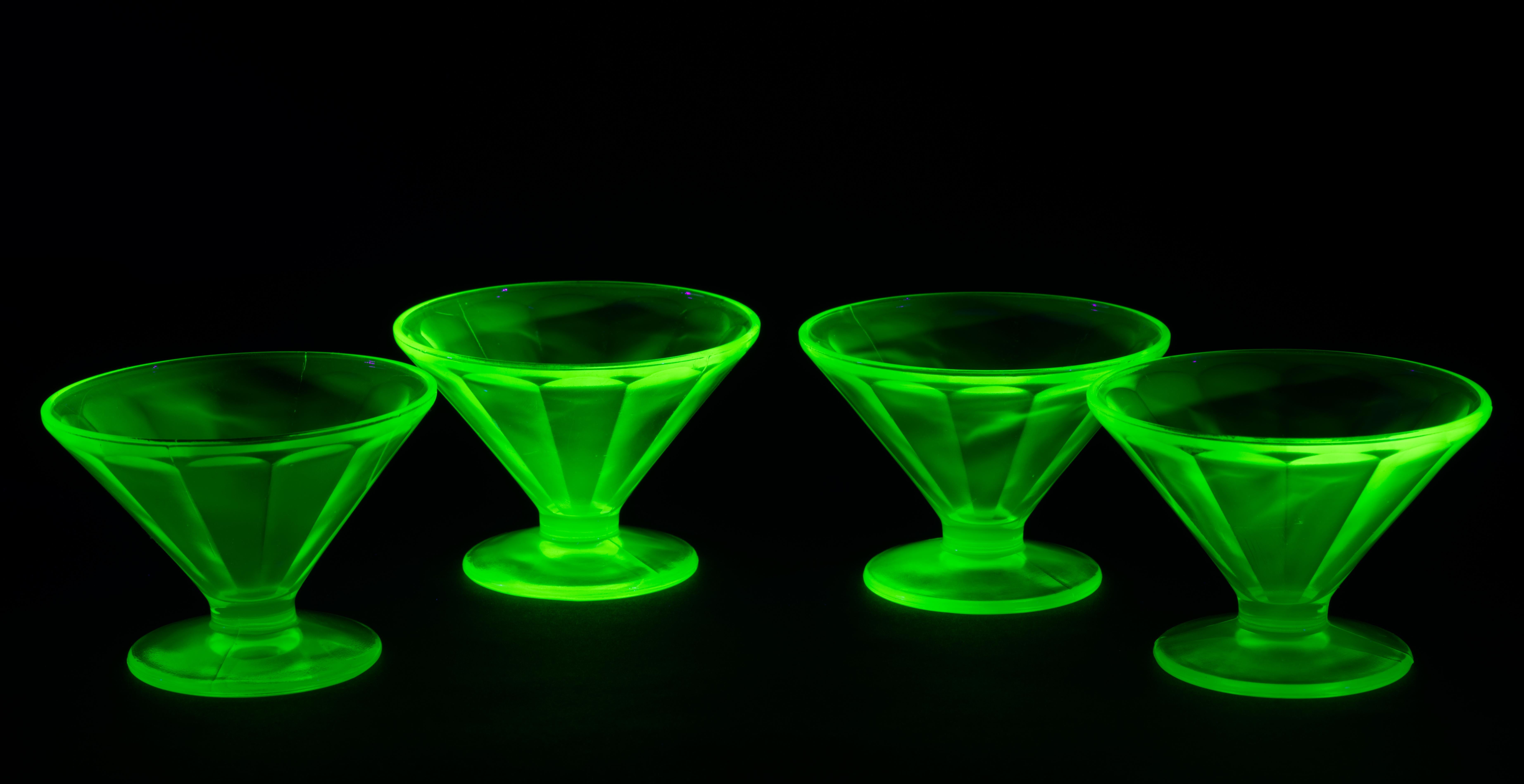  Vintage green depression glass footed bowls were made in uranium Vaseline glass with textured faceted sides of the bowls and round bases. They are glowing brightly in backlight, with textured parts having deeper glow color.
