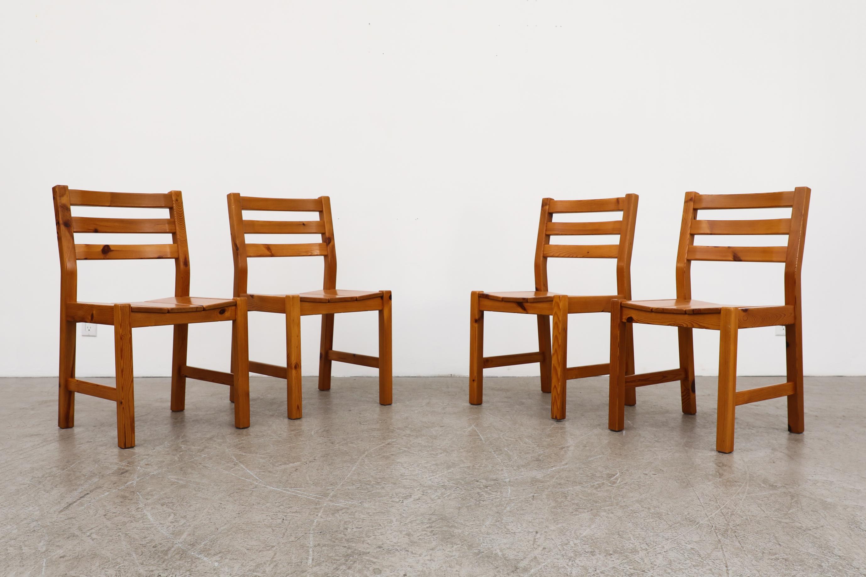 These four pine dining chairs have handsome grain patterns, ladder backs and slatted seats that slightly curve up. The chairs are in original condition with visible wear, including some light scratches and normal wear consistent with their age and