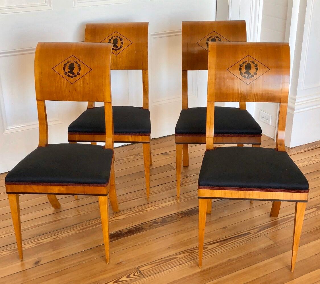 Dieses elegante Set aus vier Wiener Beistellstühlen besteht aus Kirschbaumfurnier und Ebenholz in klassischer Silhouette, umgeben von Blattriffen und umrahmt von einer Diamantintarsie. Die Sitzschiene ist mit einer Ebenholzeinlage um den Sockel