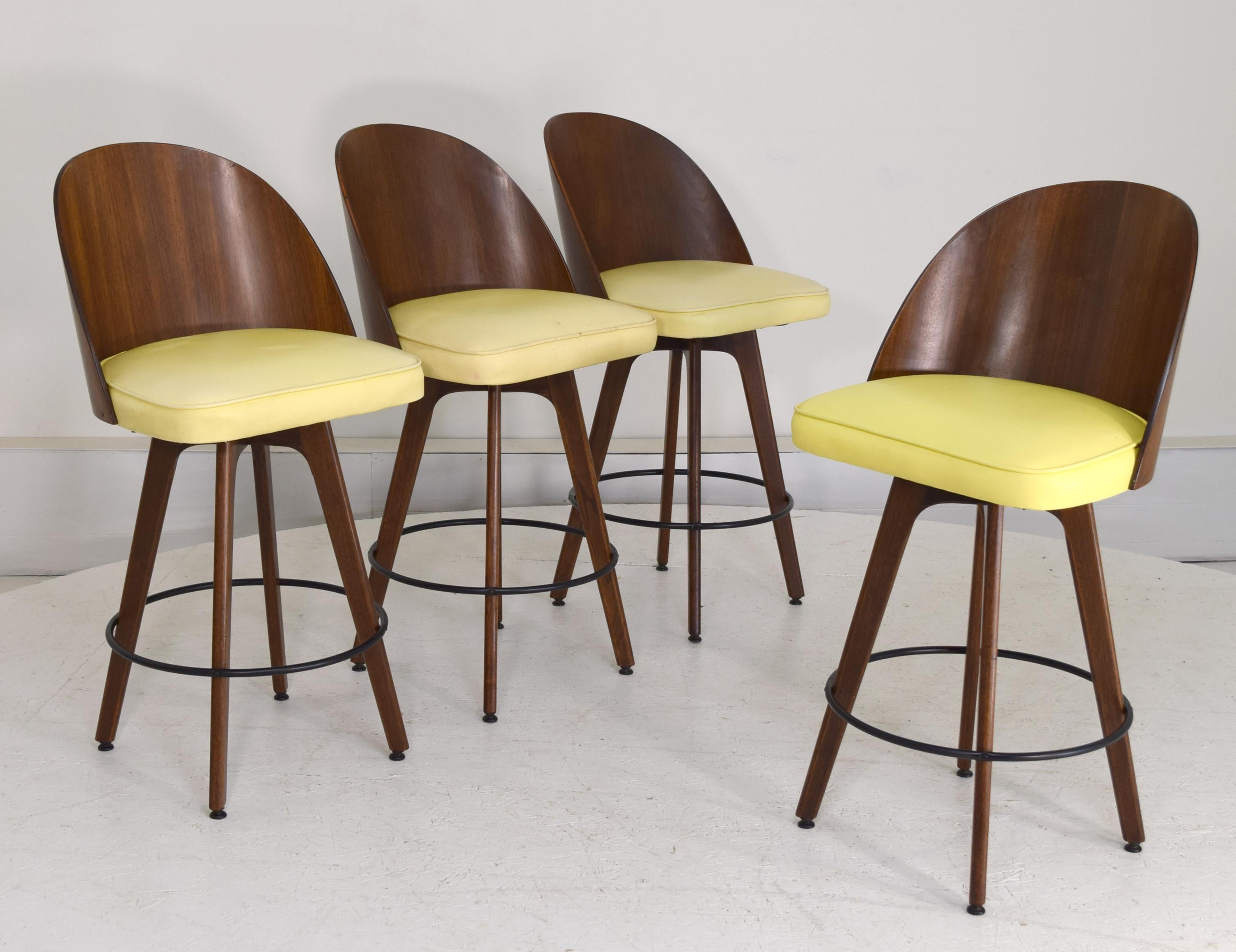 Set of 4 bar stools with swivel mechanisms produced with solid walnut leg bases and walnut plywood arched backs. Exceptional Mid century Modern design with these backs being a rare and sought-after form of the bar stools produced by the company. All