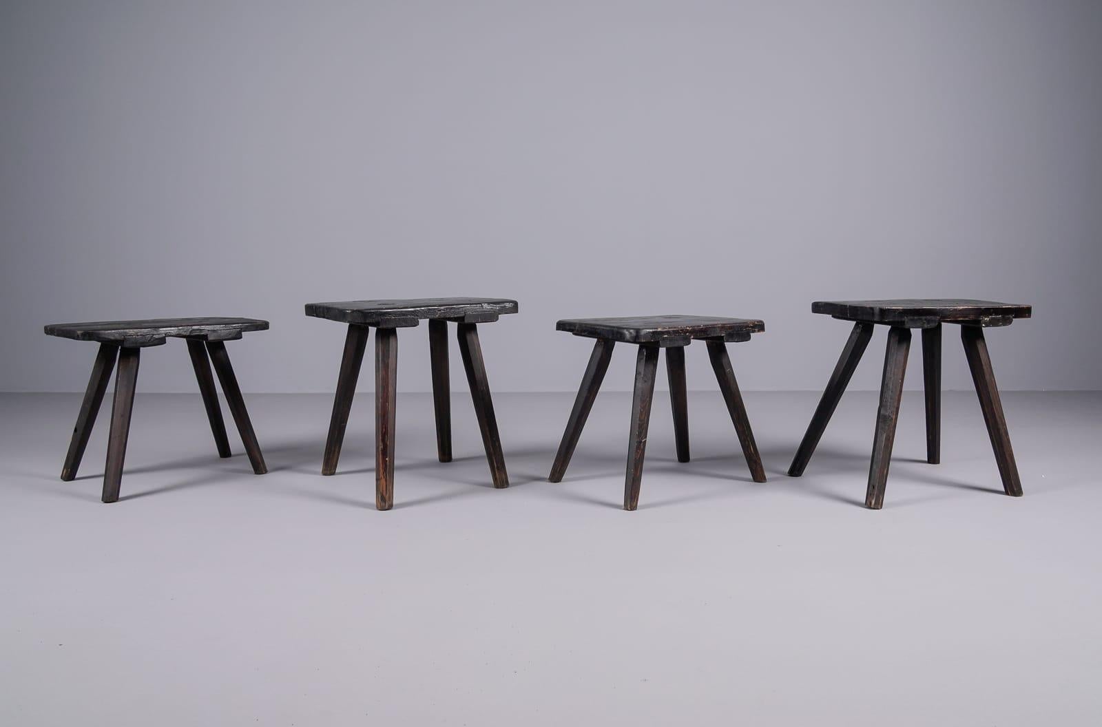 Set of 4 beautifully shaped old wooden stools, 1950s 

The original black color makes the stools elegant and slim.

Two different seat heights. 2 x 38cm and 2 x 42cm.