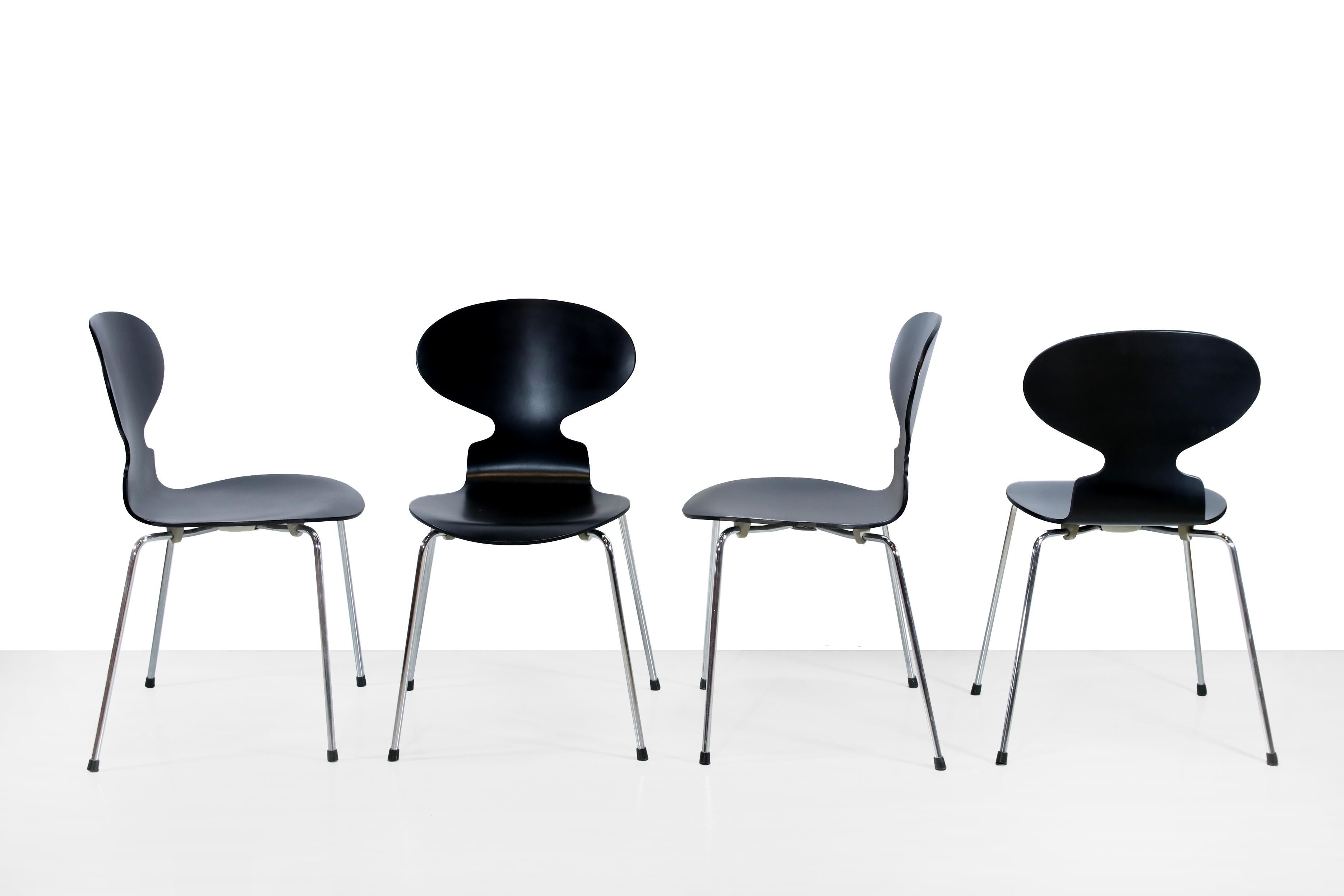Four beautiful chairs by Arne Jacobsen for Fritz Hansen. The official name of the chairs is 'chair 3100', but they are also called 'the Ant' due to their shape. This set is made of black lacquered plywood, they all have the original plastic cap on
