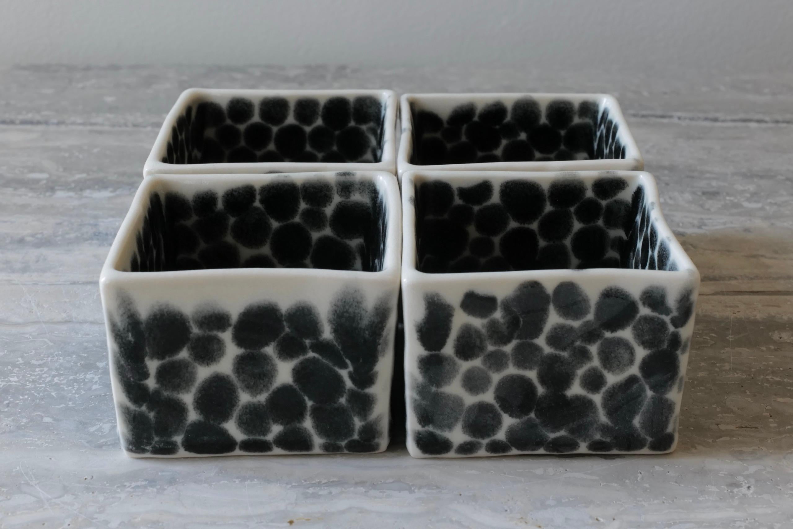 Set of 4 elegant open small cubes, which function together as a sculpture or could be filled with candles or trinkets. Hand-cast in porcelain and once bisque fired, each dot is hand-painted with shiny black glaze. An unconventional layered glazing