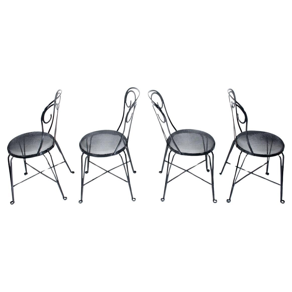 Set of 4 Art Deco Black Enamel Iron Conservatory Cafe Bistro Dining Chairs.  Featuring a hand crafted Black enameled Wrought Iron framework, criss cross support, rounded Fleur de Lis back, comfortable 14