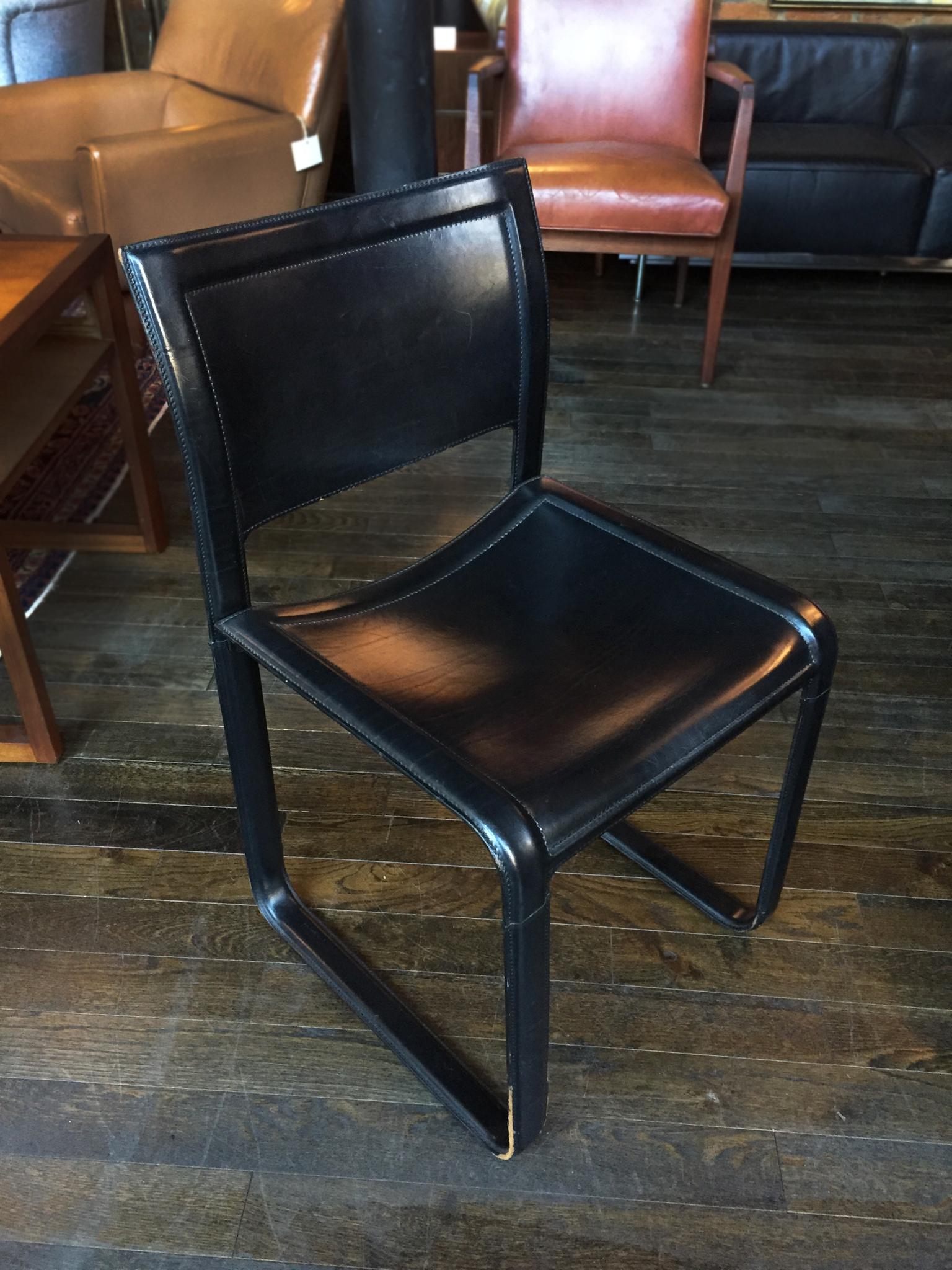 These four dining or office chairs were designed by Tito Agnoli and manufactured by Matteo Grassi, circa 1970s-1980s. They are comprised of a sturdy metal frame and black leather wrapping. The leather tautly covers the entire frame. The visible