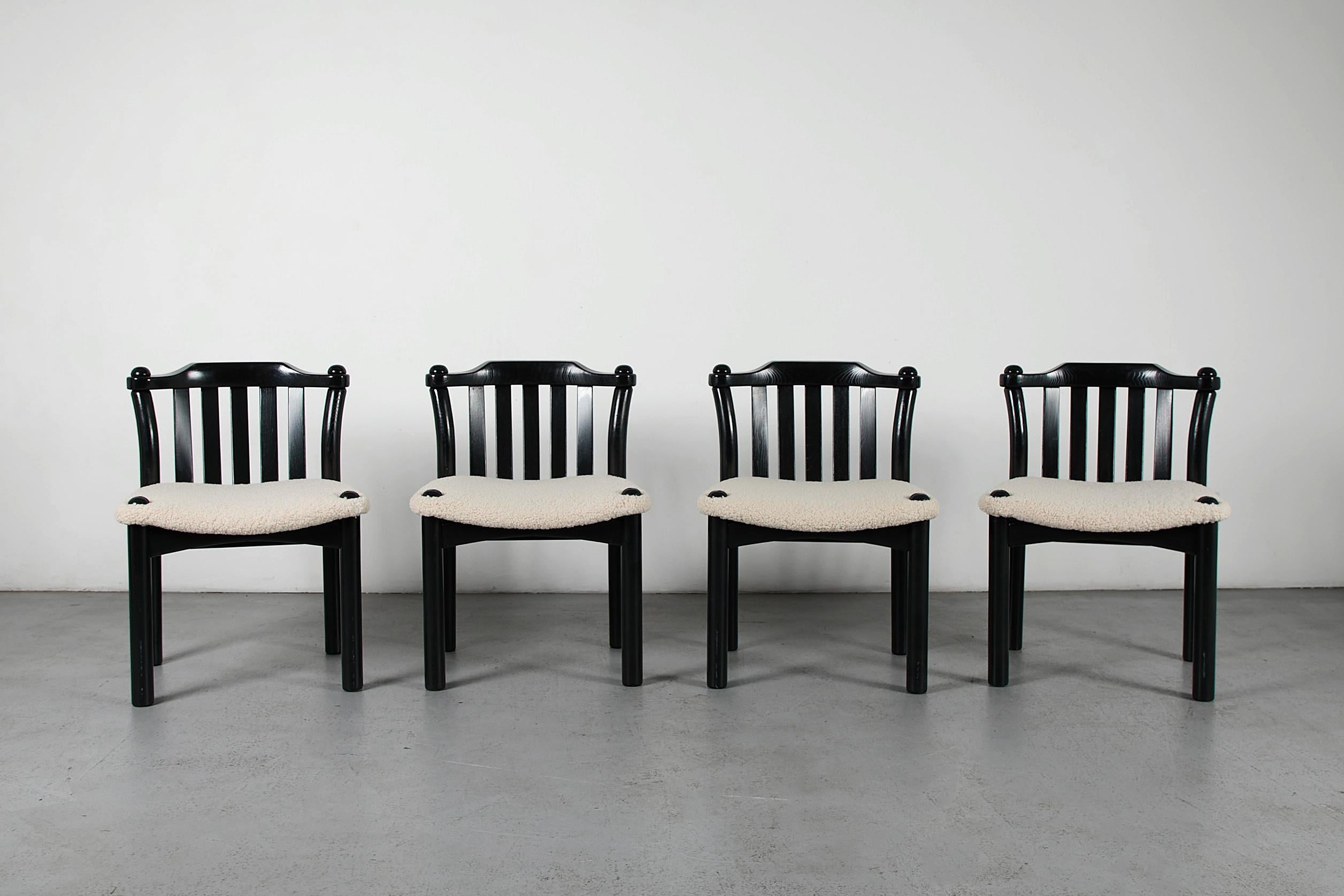 Un caratteristico set di quattro sedie postmoderne con un'ampia struttura laccata nera e sedute imbottite in sherpa. Il design mette in mostra le espressive gambe in legno arrotondate che penetrano nella struttura e si estendono con piani