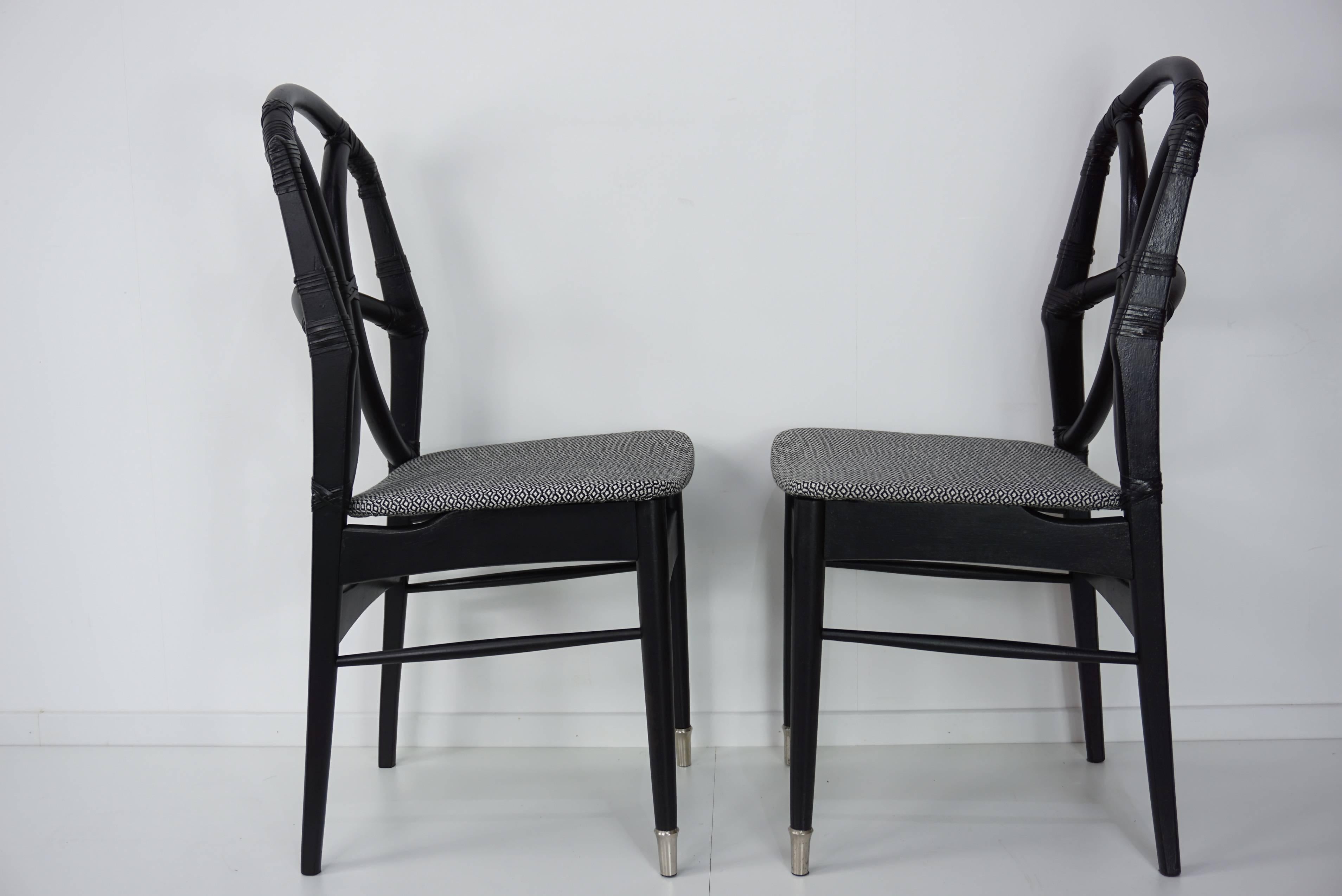 Elegant and amazing set of four black wooden structure with leather and rattan backrest, black and white fabric chairs design from the 1950s.