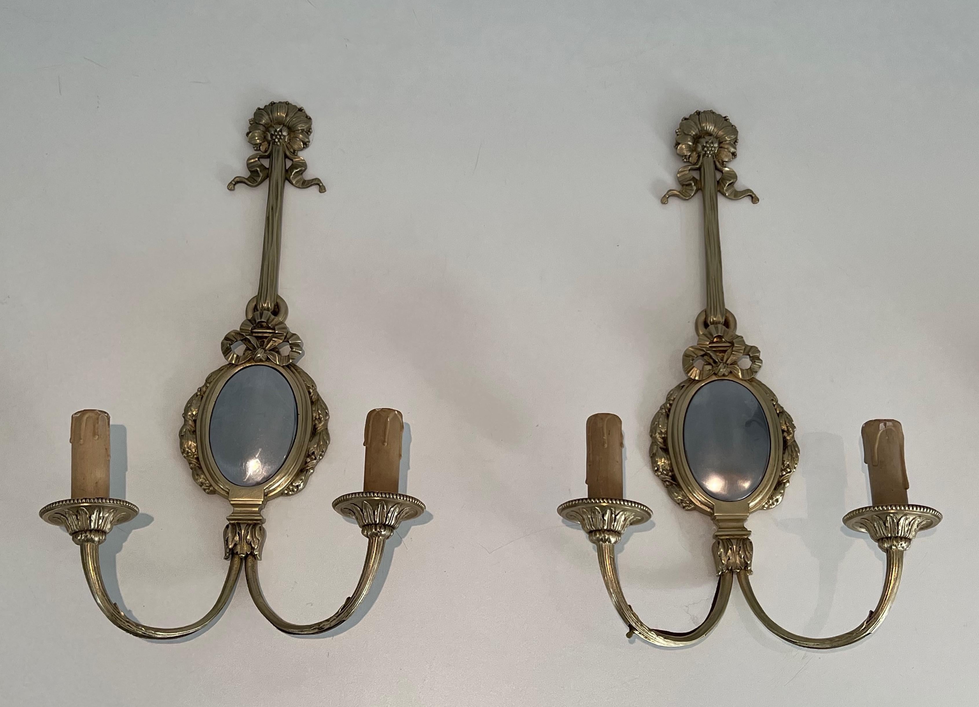 This set of 4 Louis the 16th style wall sconces is made of chiseled bronze decorated with bows and ribbon and comprising a domed oval part in chrome. This is a French work, circa 1930.