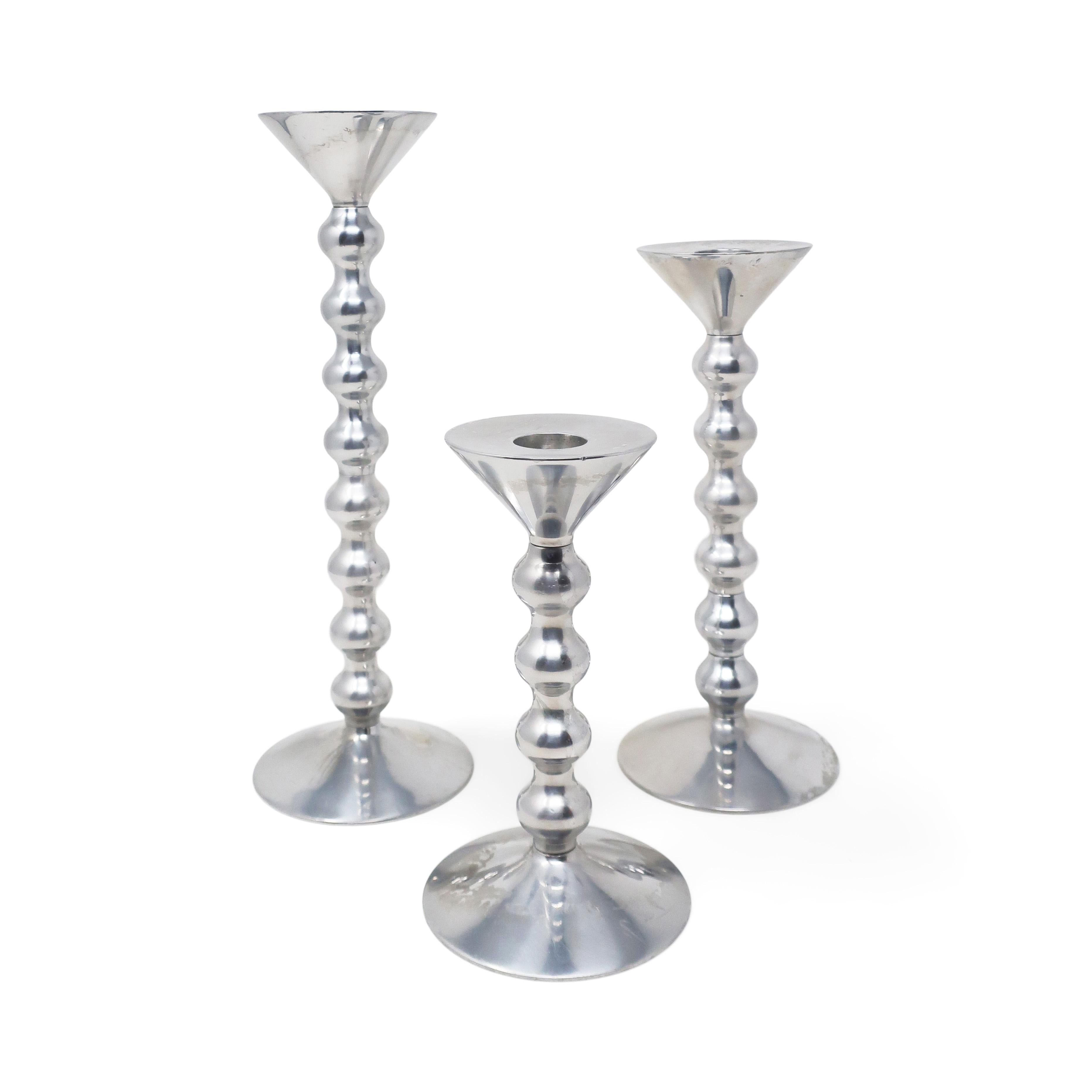 A fantastic set of 4 polished aluminum candlesticks designed by Alessandro Mendini in 2002 for Alessi, the Italian housewares powerhouse. Each candleholder consists of a base, stem piece, and top, which screw together. There are two different size
