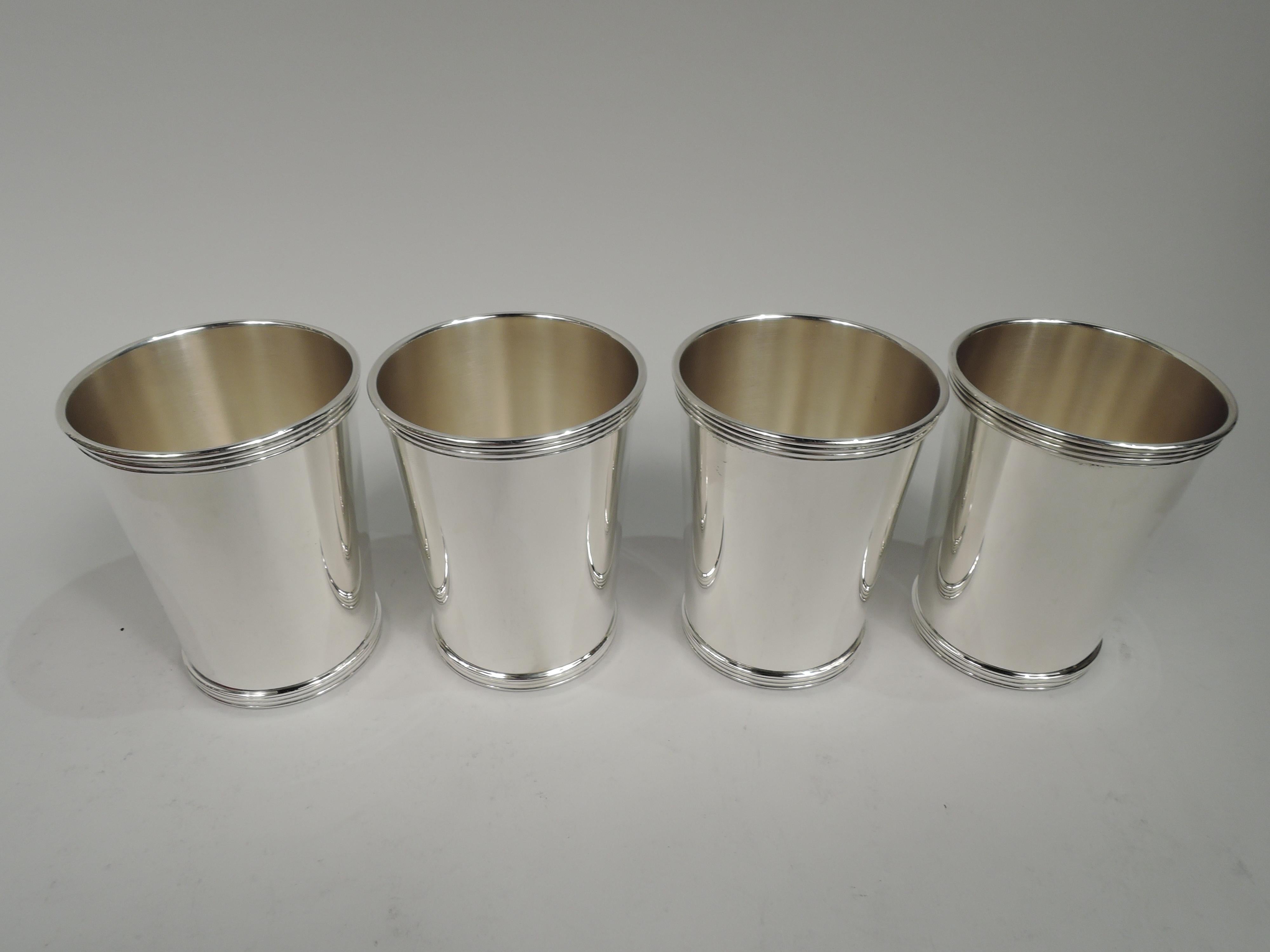 Set of 4 sterling silver mint julep cups. Retailed by Cartier in New York. Each: Traditional form with straight and tapering sides and reeded rim and base. In red leather-bound case with fitted velvet. Cover interior has gilt retailer’s stamp. Cups