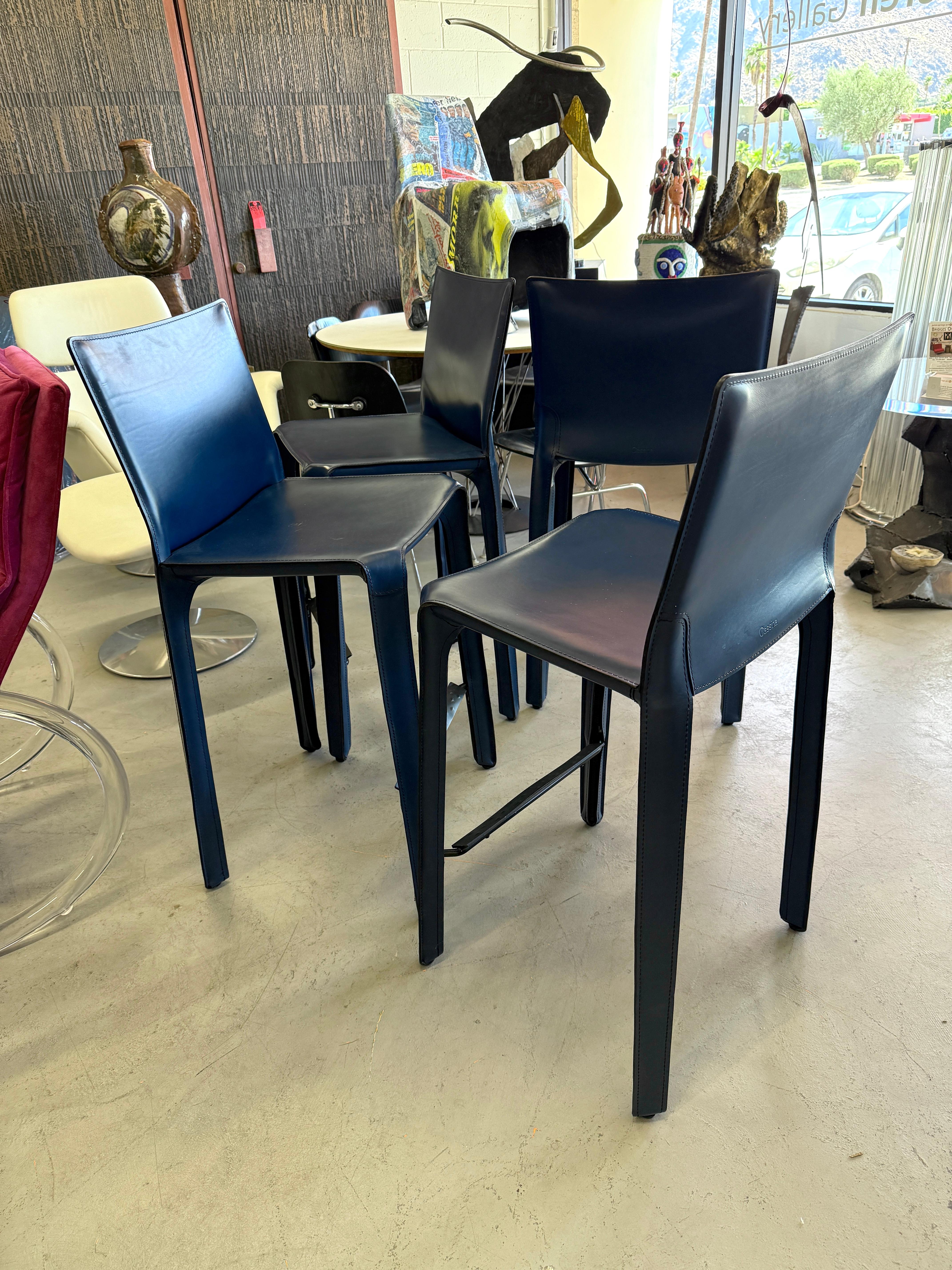 A lovely set of 4 Mario Bellini Cassina counter stools in a beautiful blue leather. These are the model 410. There were ordered and delivered in 2022 and very lightly used in a second home. They are in good overall condition with some minor marks 