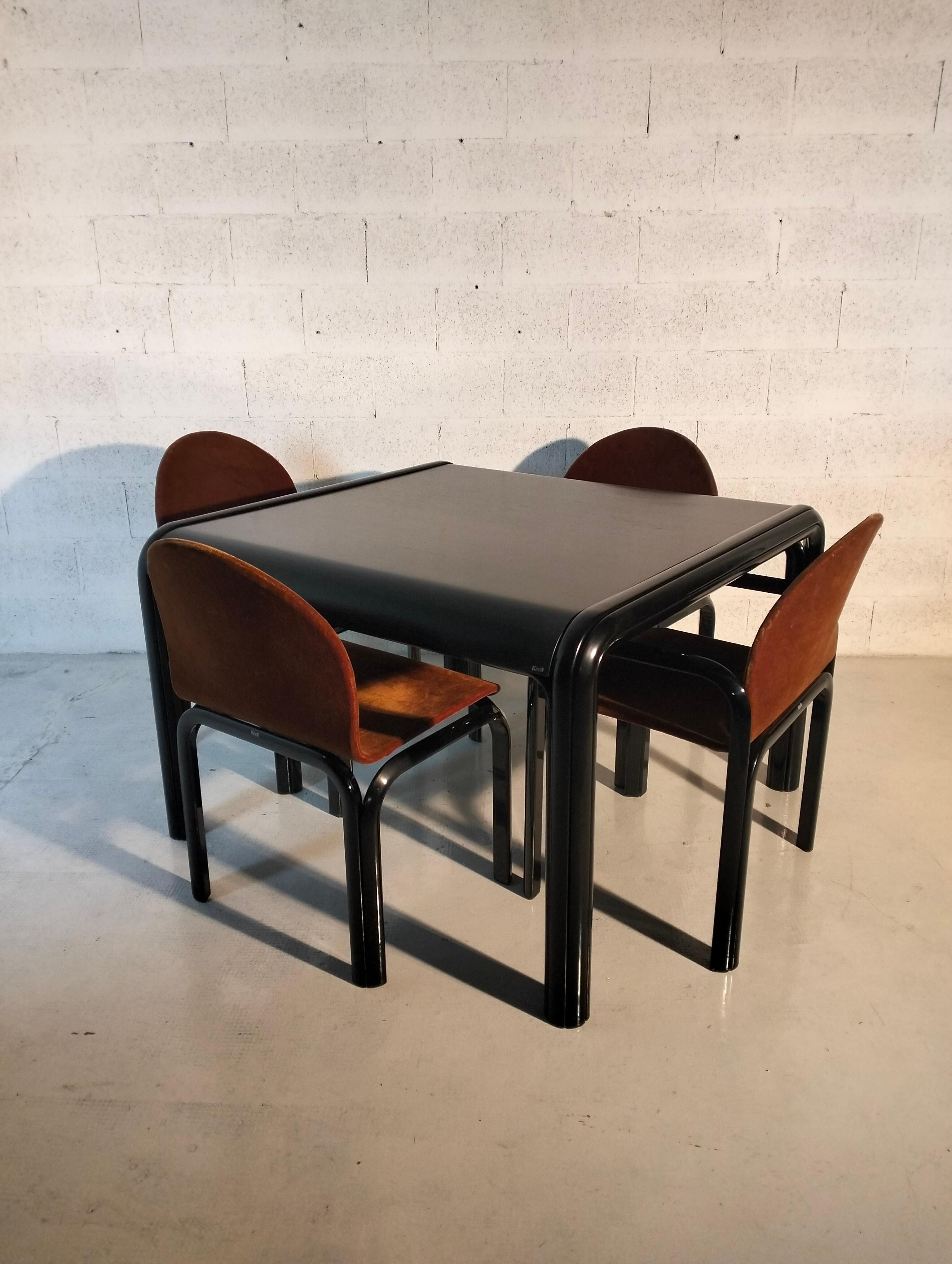 A mid century modern dining table and four chairs designed by Gae Aulenti and made by Knoll. 
The table with a black rolled steel frame and black laminate top. 
The chairs with black extruded aluminum frames and brown fabric,  2 with armrests and 2