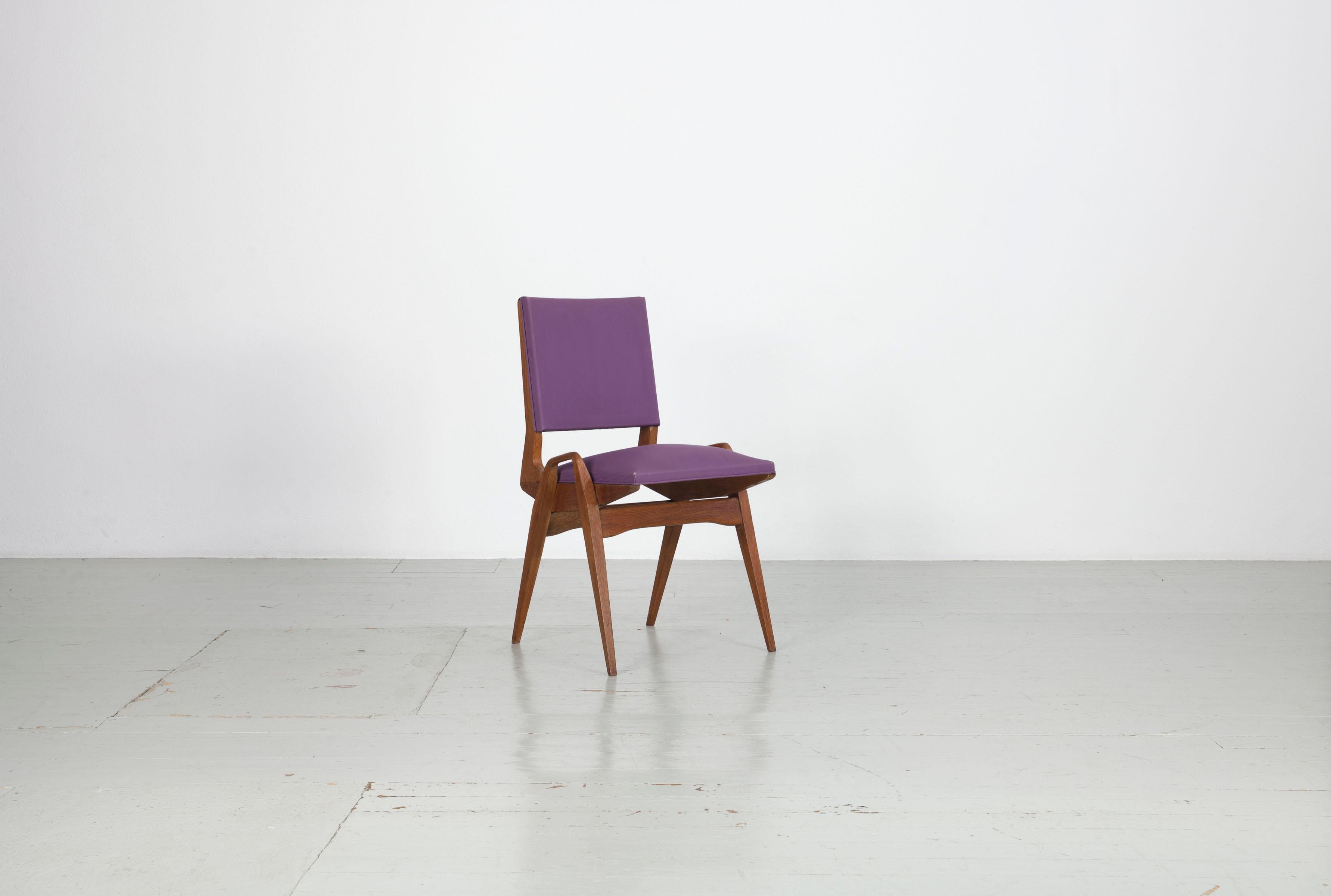 This authentic set of four chairs by Maurice Pré dates back to the 1950s and shows typical signs of wear consistent with age. The original blackberry colored Skai upholstery is preserved, with some visible wear on the front corners of the seats, and