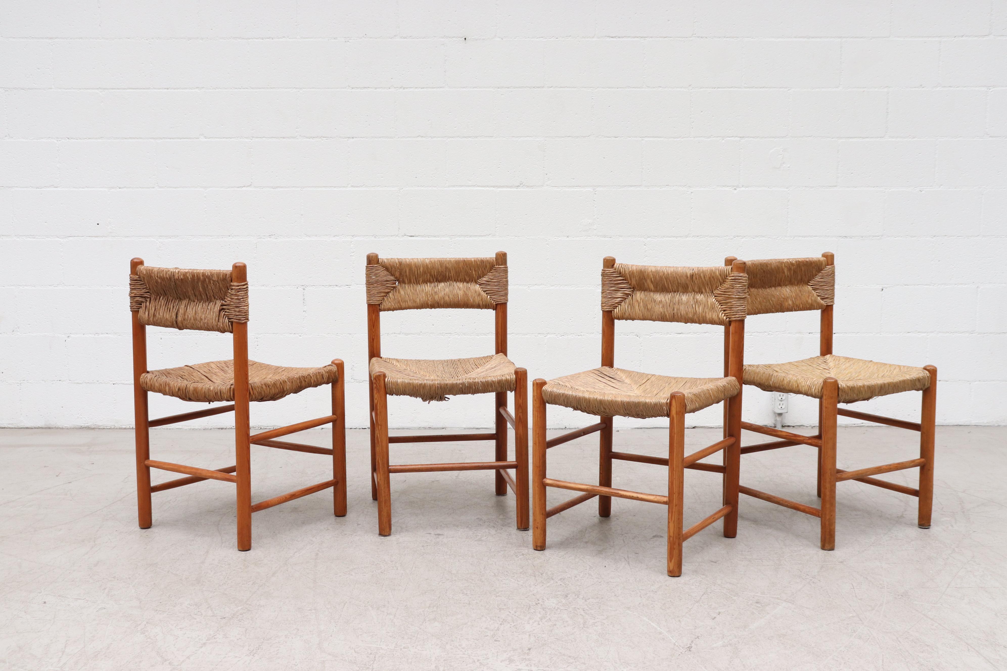 Set of 4 Charlotte Perriand Style Pine and Rush Dining Chairs. Lightly Refinished Pine Frames with Original Woven Rush Seat and Back Rest. In Very Original Condition with Visible Wear, Visible Breakage of Rush and Patina to Wood. Two Sets Available,