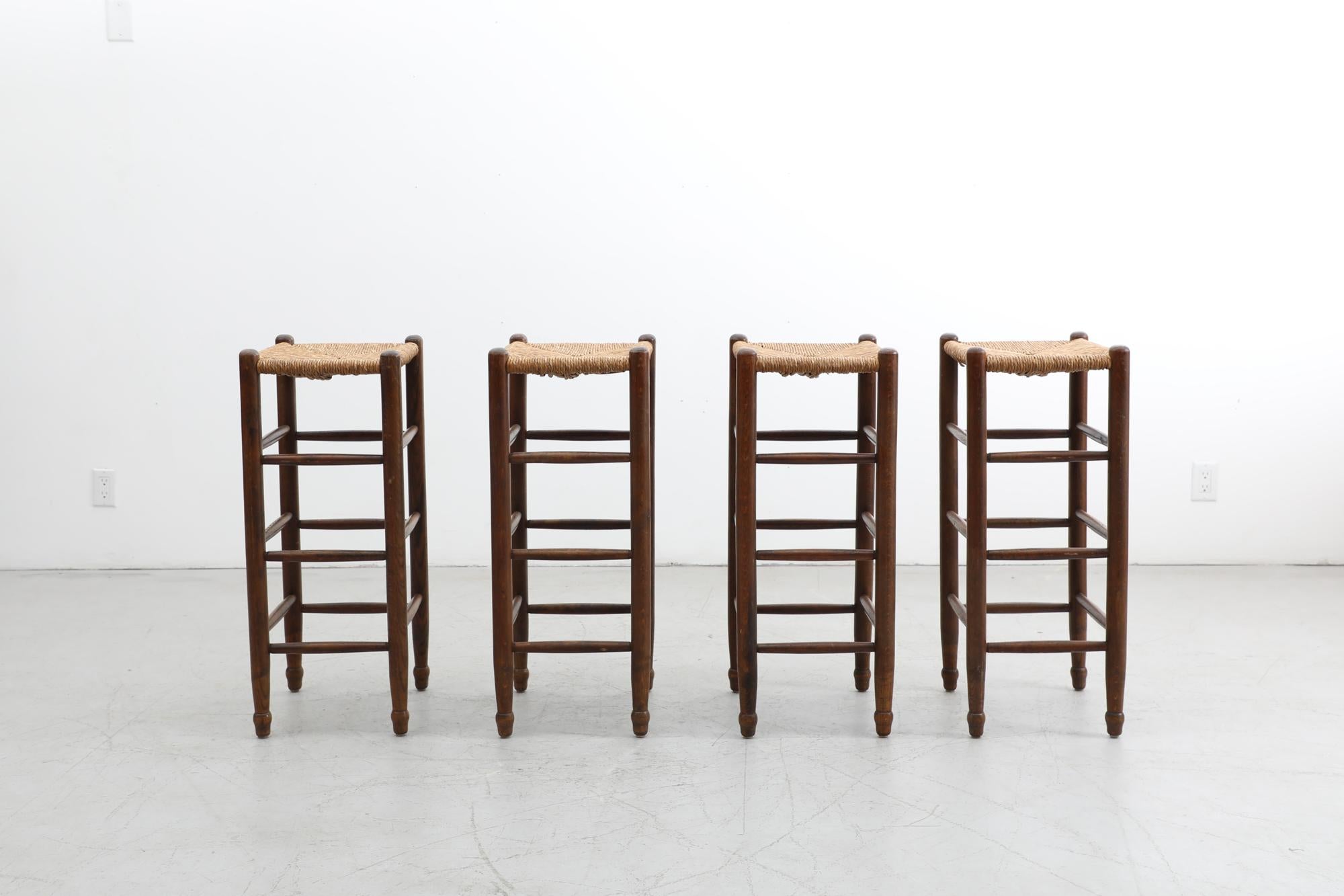 Set of 4 Charlotte Perriand style tall rush bar mid century stools with dark stained pine frames and thick woven rush seating . Seat height is 32.5