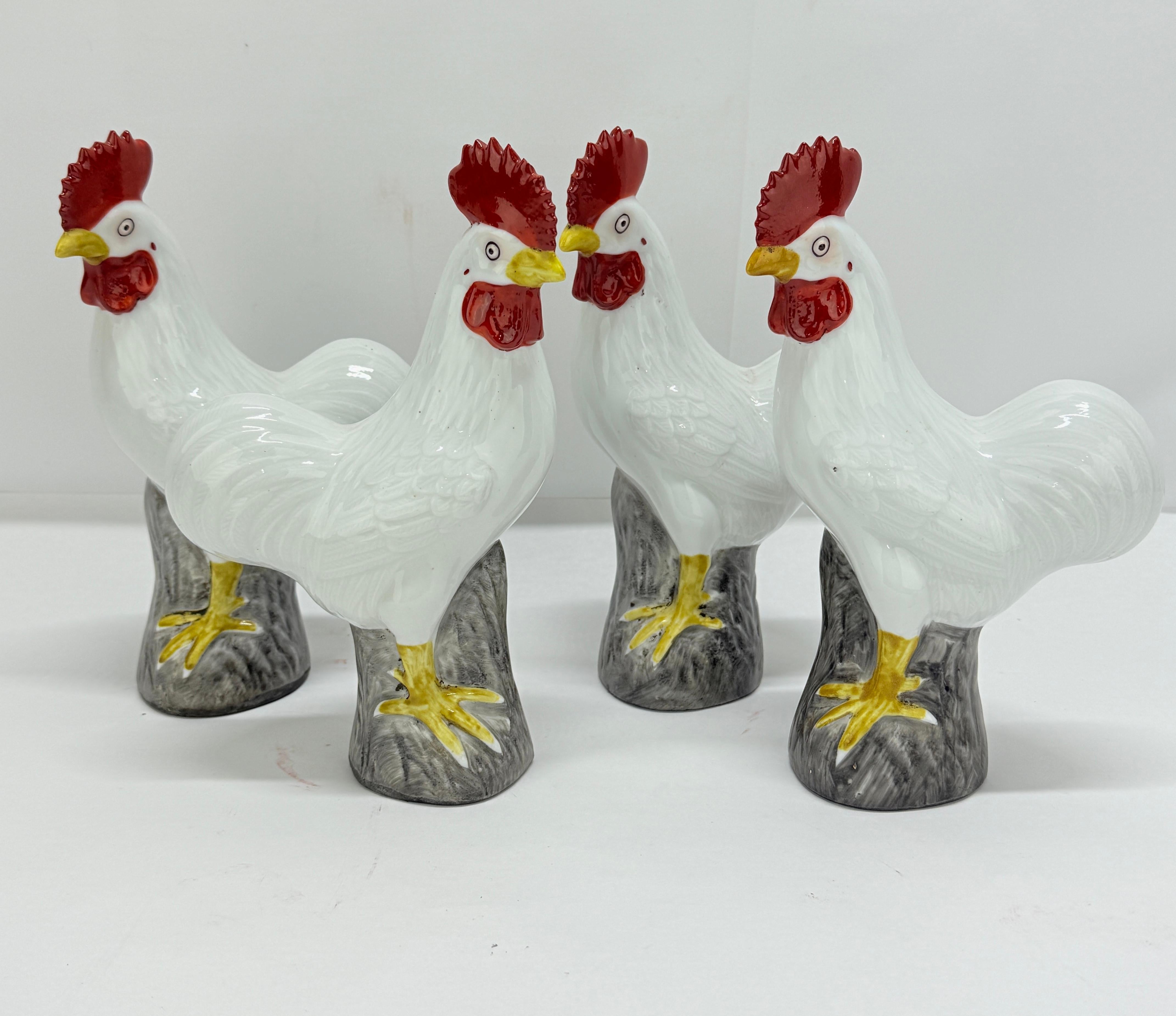 A whimsical and well-modeled set of four porcelain rooster-form figures in the Chinese Export style, likely dating to the mid-20th century. Each figure is delicately hand-painted, with vivid white glazed bodies accented by bold scarlet combs and